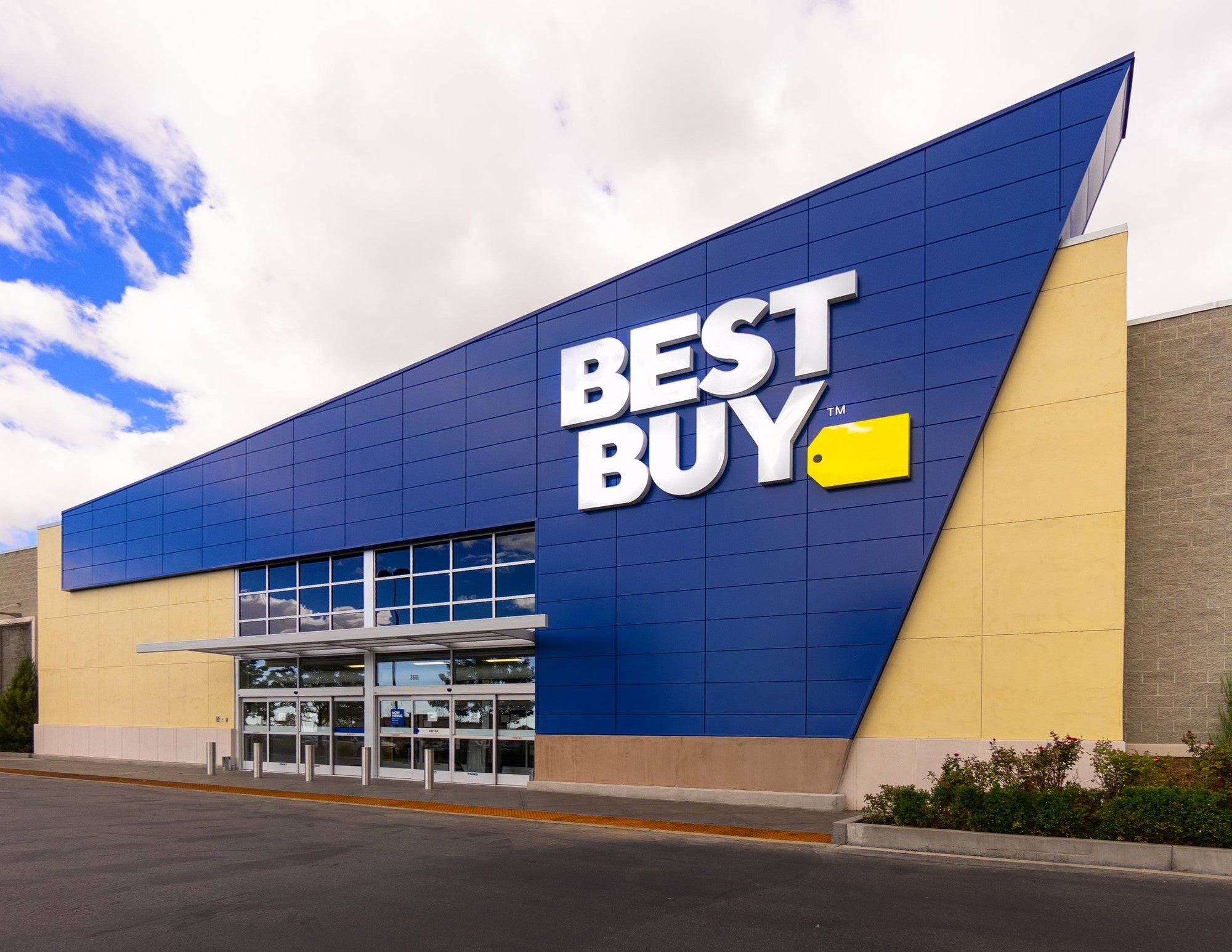 buy 桌布 壁紙 — 一間現代化的Best Buy商店，在部分多雲的天空下，有醒目的藍色和黃色標誌。