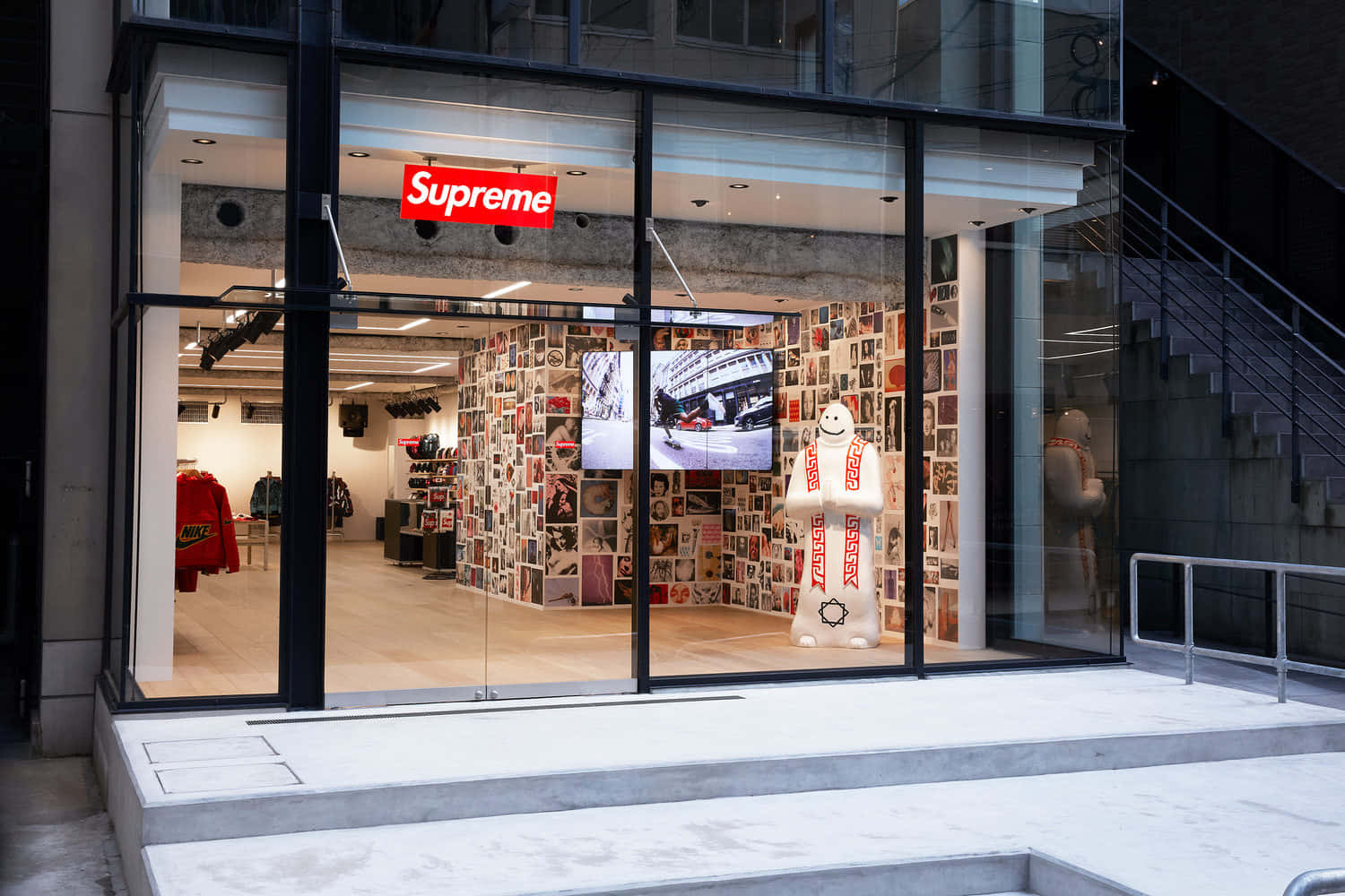 supreme 桌布 壁紙 — 一間現代化的Supreme商店，玻璃外牆展示了一個巨大的白色雪人雕像，牆上佈滿了復古照片。