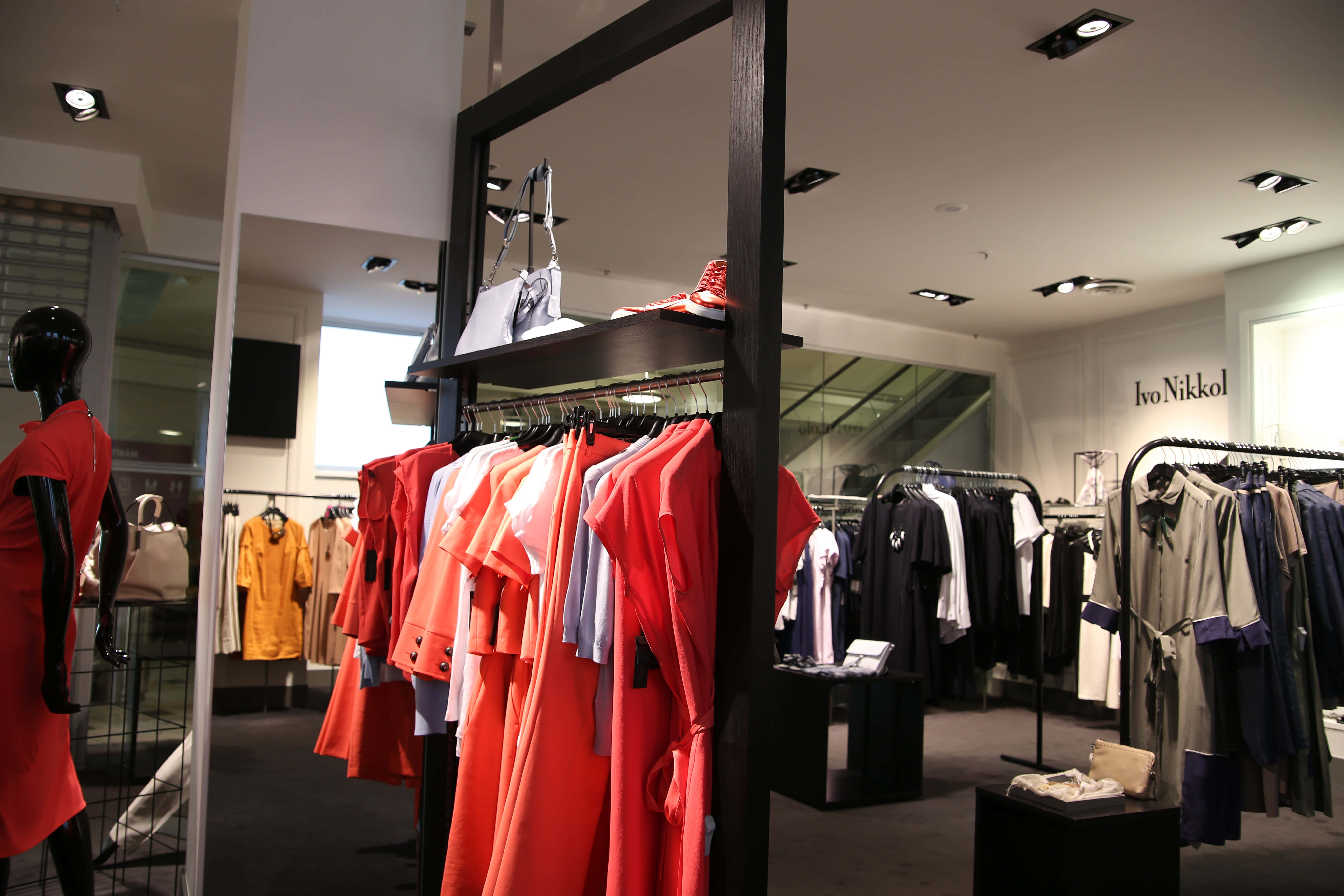 Shopping 桌布 壁紙 — 一間現代精品店在陳列架上展示鮮豔的紅色和白色服裝，配有黑色人體模型和極簡照明。