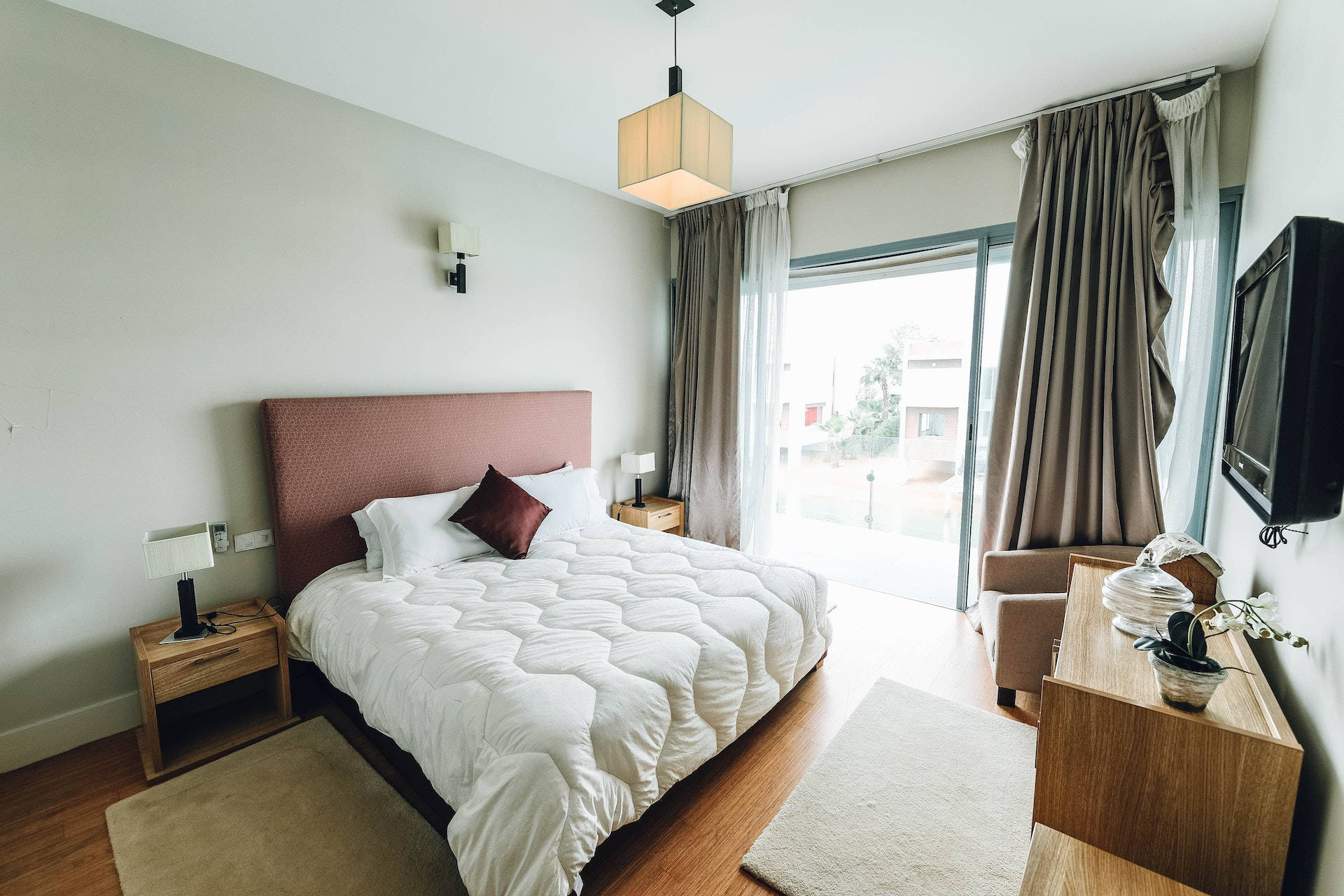 bed 桌布 壁紙 — 一間現代臥室，配有一張大床、木製家具和通往陽台的玻璃門。