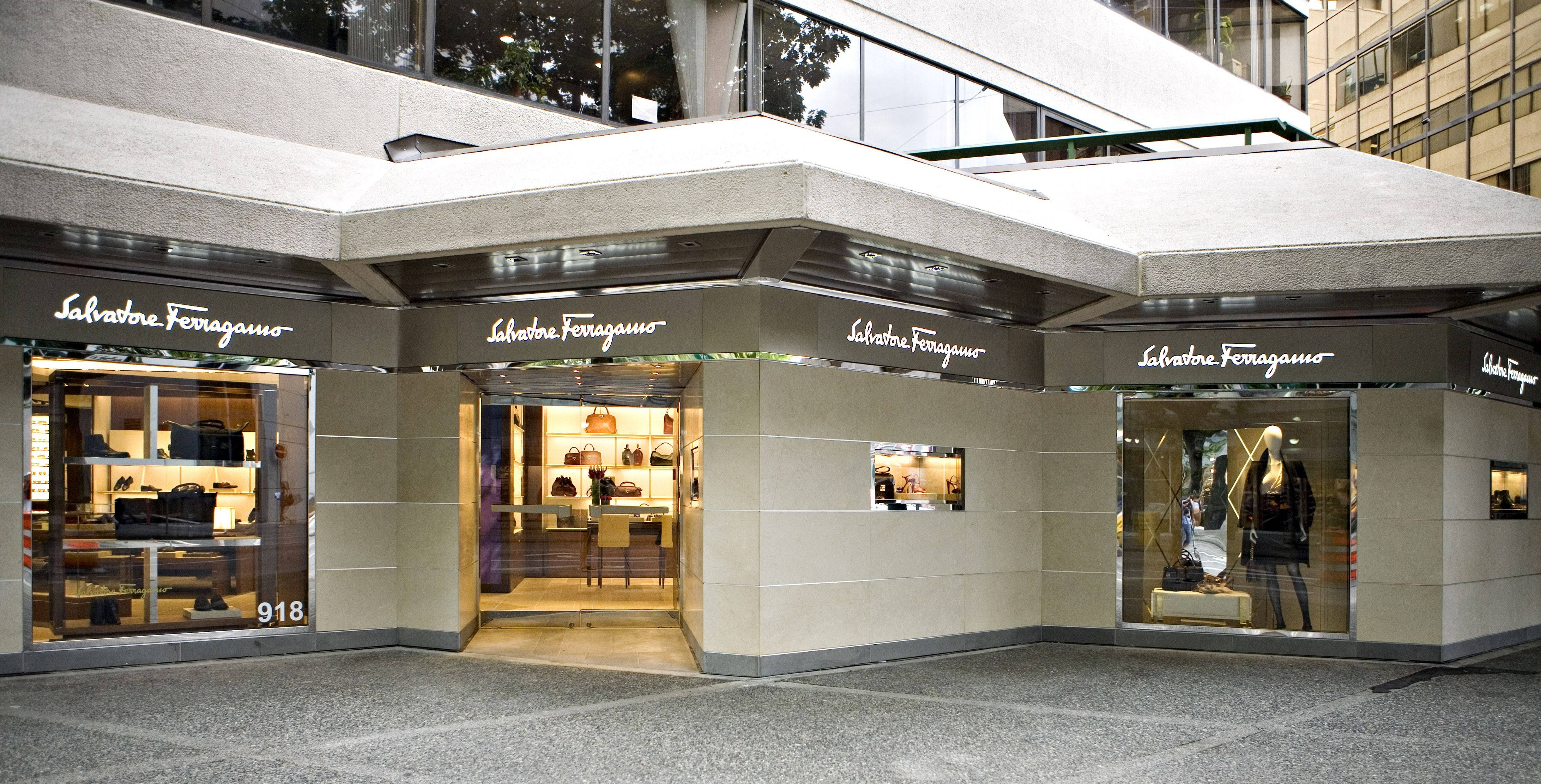 Ferragamo 桌布 壁紙 — 一間現代豪華精品店，玻璃櫥窗在溫暖的室內燈光下展示手提包和鞋子。