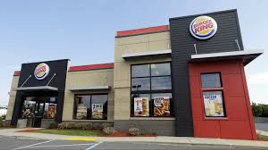 Burger King 桌布 壁紙 — 一間現代風格的漢堡王餐廳，外牆為紅、黑、米色，在清澈的藍天下。