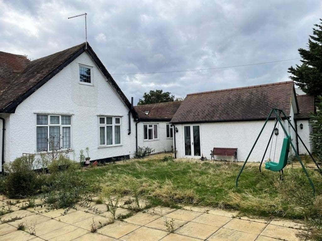 Property 桌布 壁紙 — 一間白色小屋，設有瓷磚庭院和雜草叢生的草坪，在陰天之下有一個綠色鞦韆套裝。