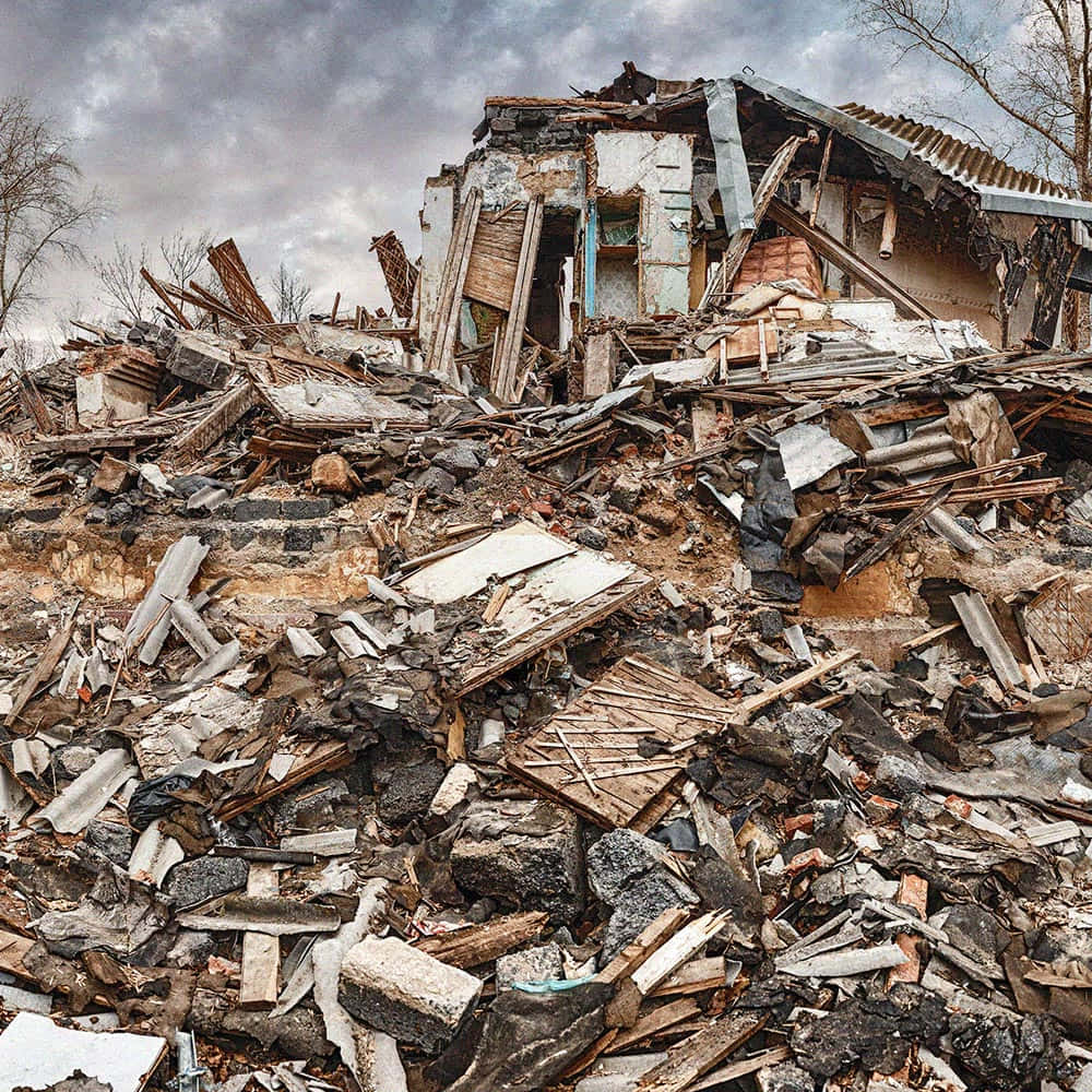 Earthquake 桌布 壁紙 — 一間破爛的房子在陰天下廢墟中，碎片散落在前景。