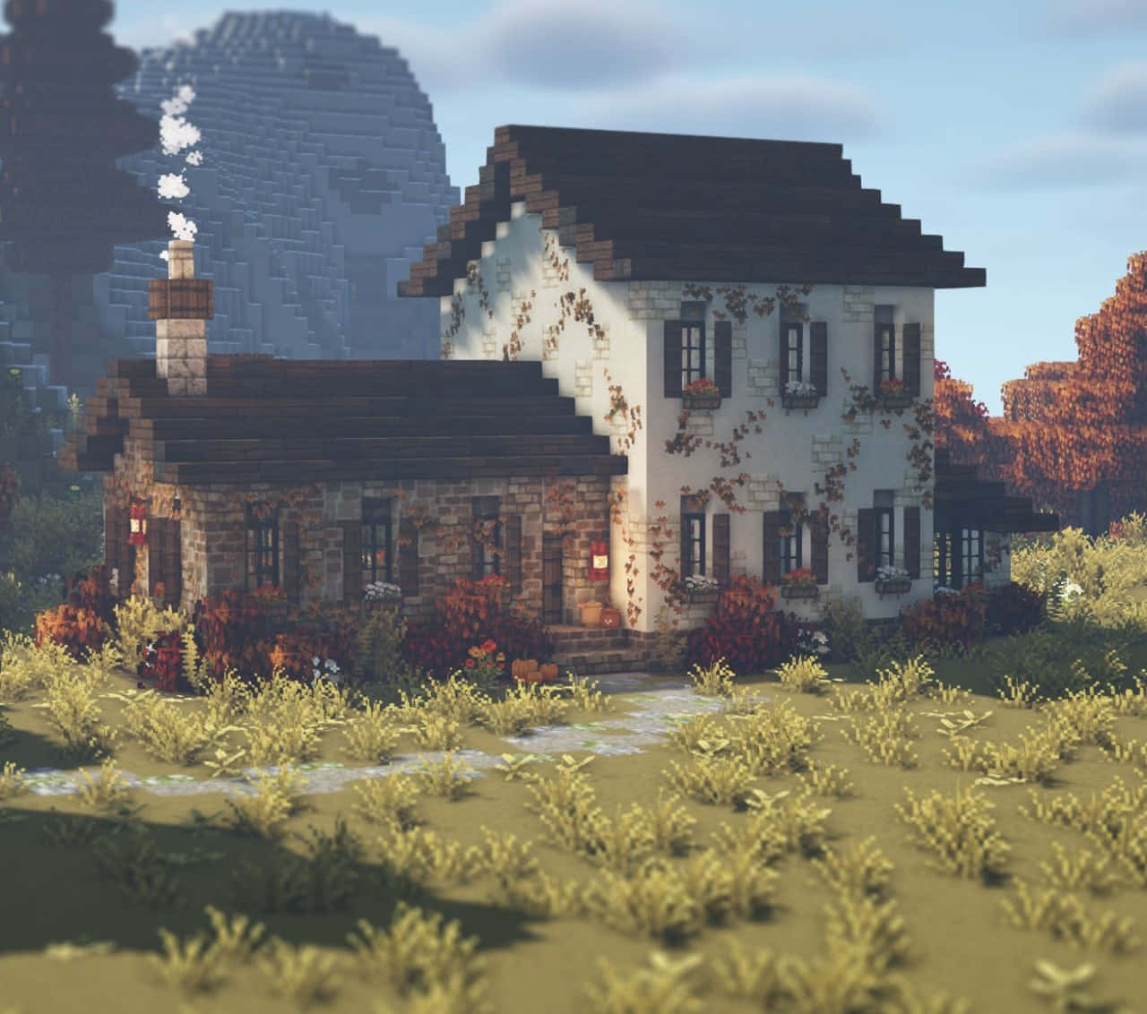 Minecraft Architecture 桌布 壁紙 — 一間舒適的像素風格石頭小屋，周圍有常春藤和南瓜，坐落在晴朗天空下的草地上，背景有山。