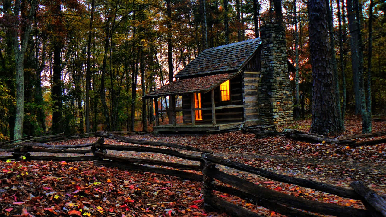 Fall Cabin 桌布 壁紙 — 一間舒適的木屋，溫暖發光的窗戶，隱藏在黃昏時分茂密的秋林中。