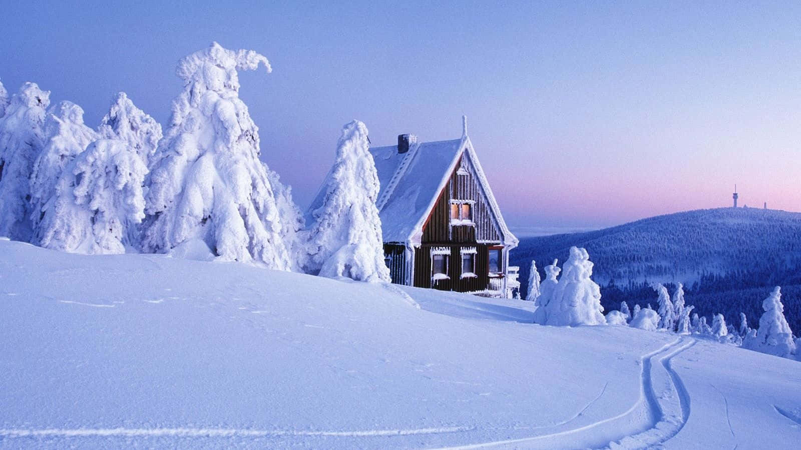 High Resolution Snow 桌布 壁紙 — 一間舒適的木屋坐落在暮色中白雪覆蓋的山林裡，樹木掛滿霜雪，滑雪道蜿蜒穿過純淨的白色景觀。