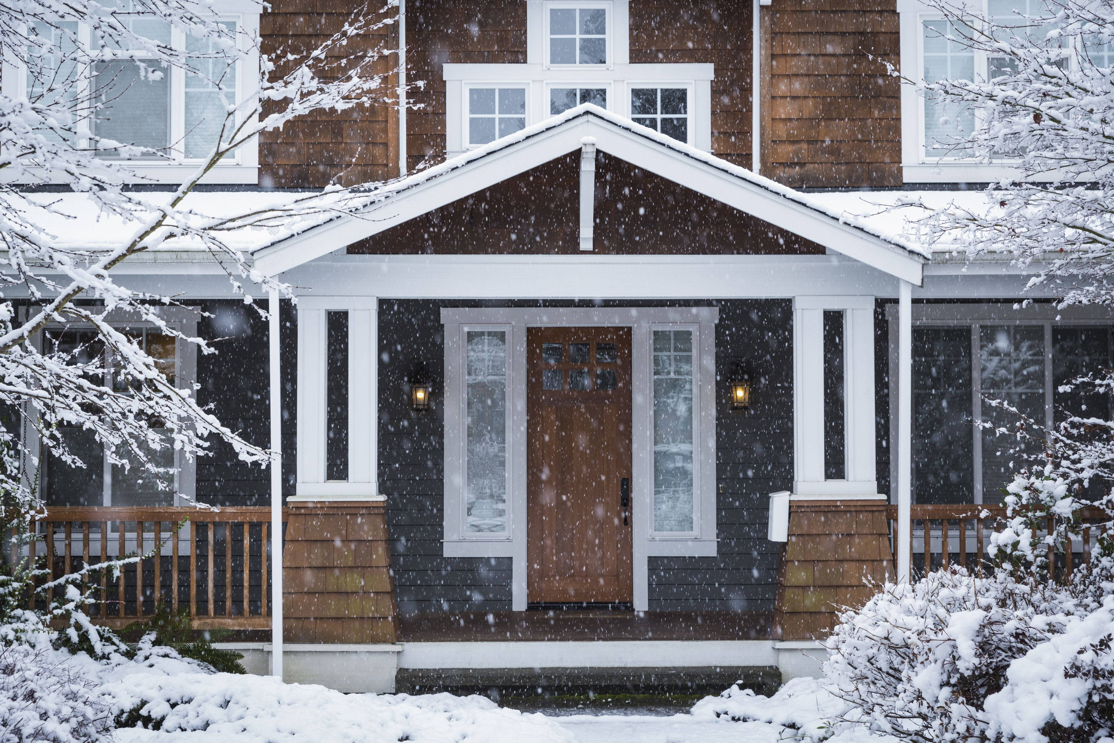 Winter House 桌布 壁紙 — 一間舒適的深灰色房屋，帶有白色飾邊和積雪覆蓋的樹枝，矗立在輕柔的降雪中。