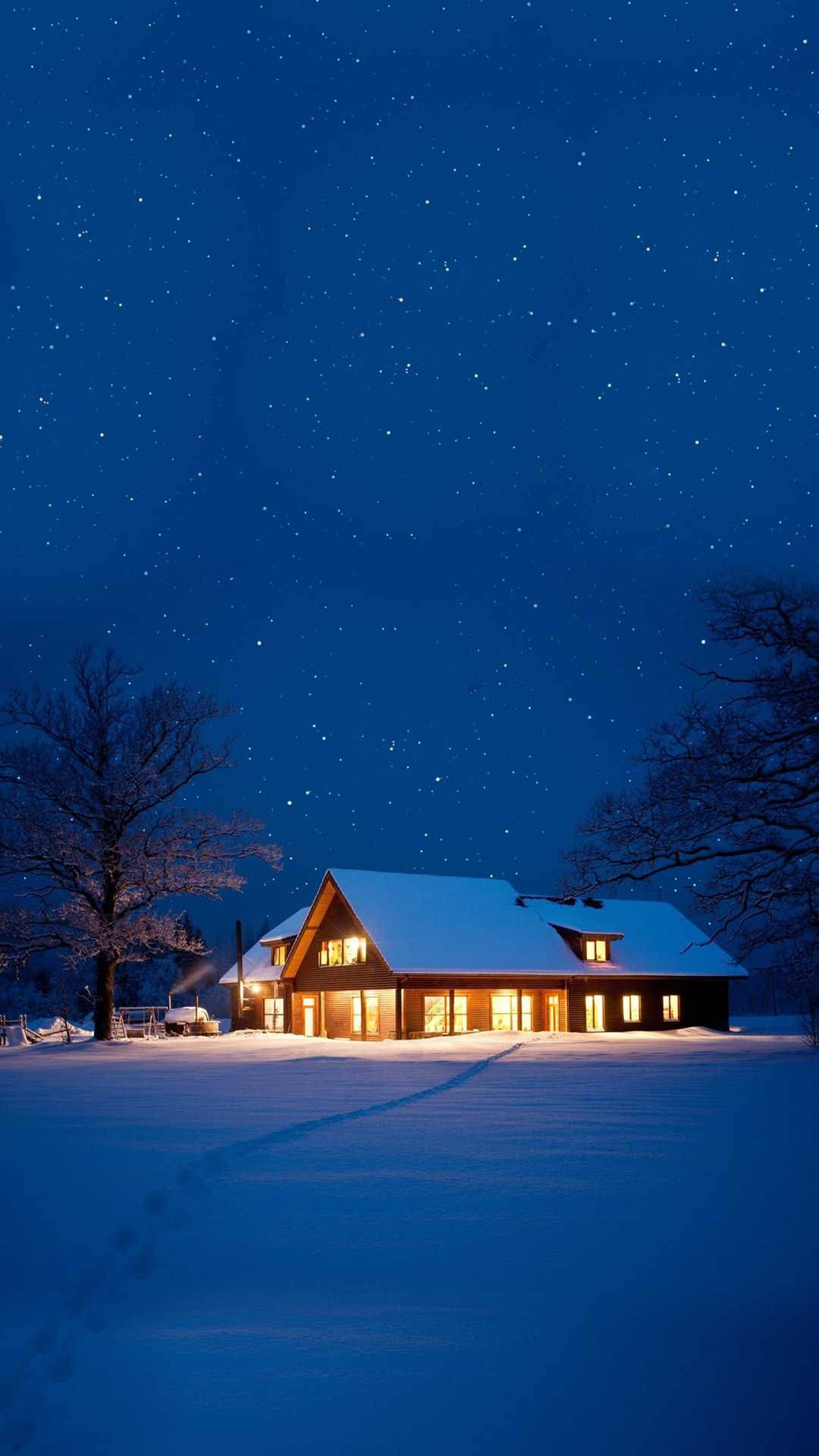 冬季房屋 桌布 壁紙 — 一間舒適的雪覆蓋小屋在廣闊的星夜冬季天空下溫暖地發光。