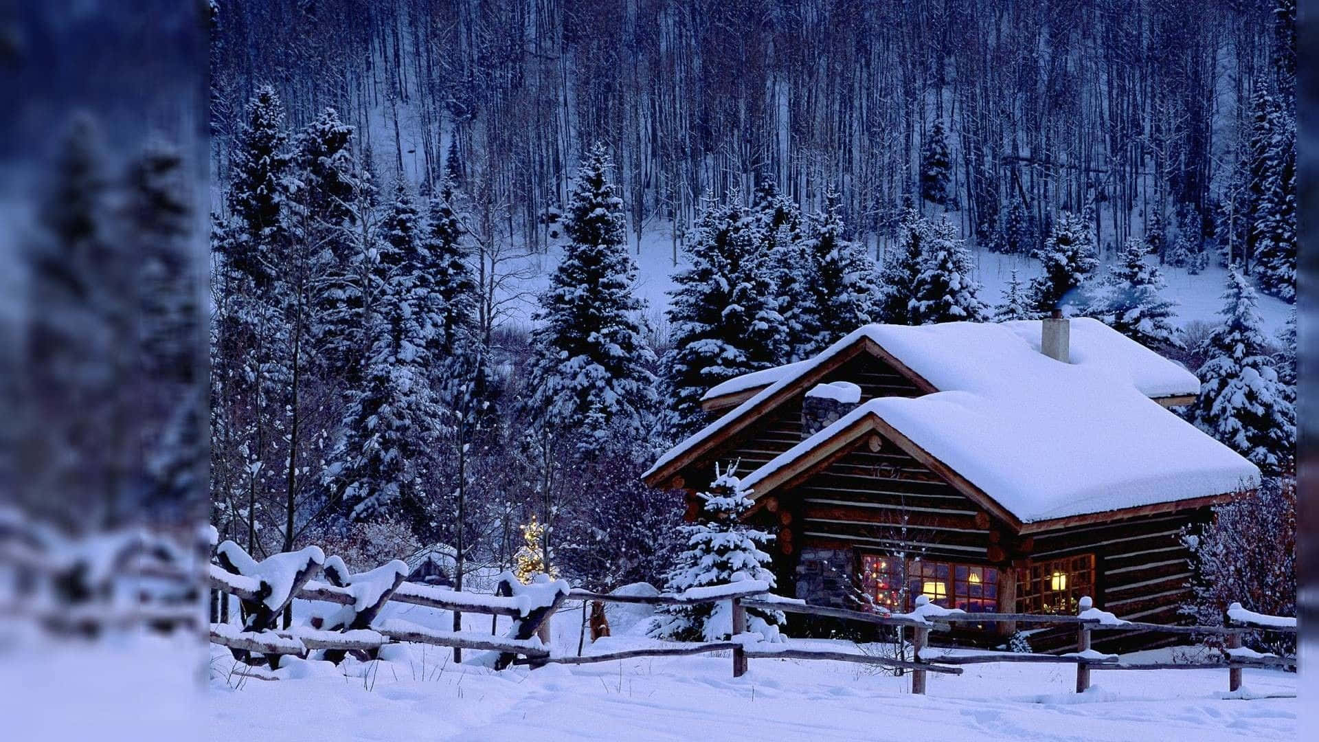 Winter Scenery Desktop 桌布 壁紙 — 一間舒適的雪覆蓋小木屋坐落在冬季森林中，窗戶透出溫暖的燈光。