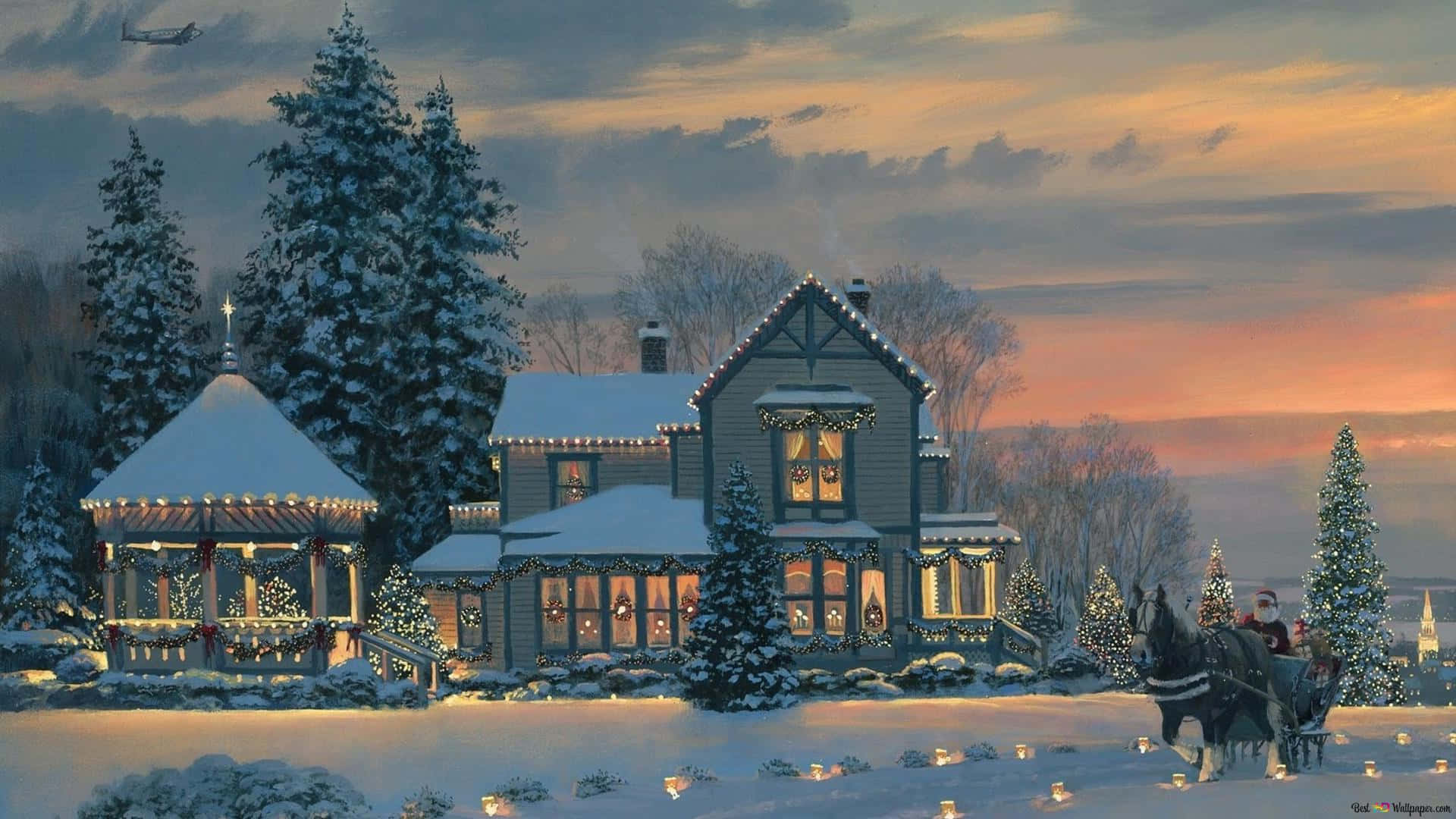 Winter Christmas Desktop 桌布 壁紙 — 一間舒適的雪覆蓋維多利亞式房屋，裝飾著節日燈飾和花環，在暮色天空中溫暖地發光，一輛雪橇經過。