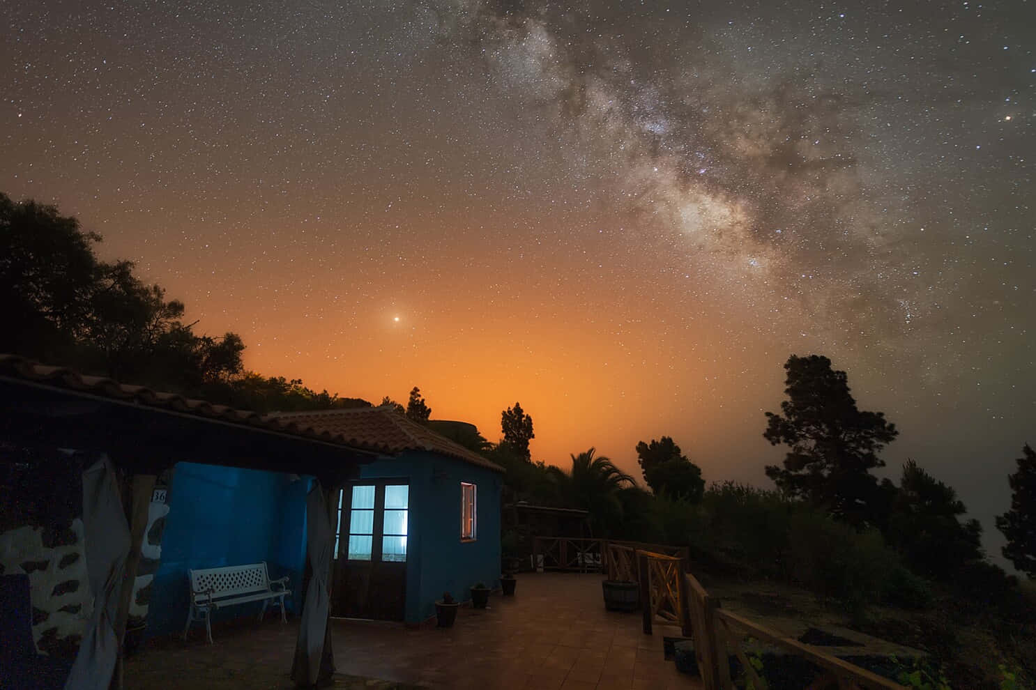 火星 桌布 壁紙 — 一間藍色房子在充滿星星和銀河的鮮豔橙色暮色天空下發光。