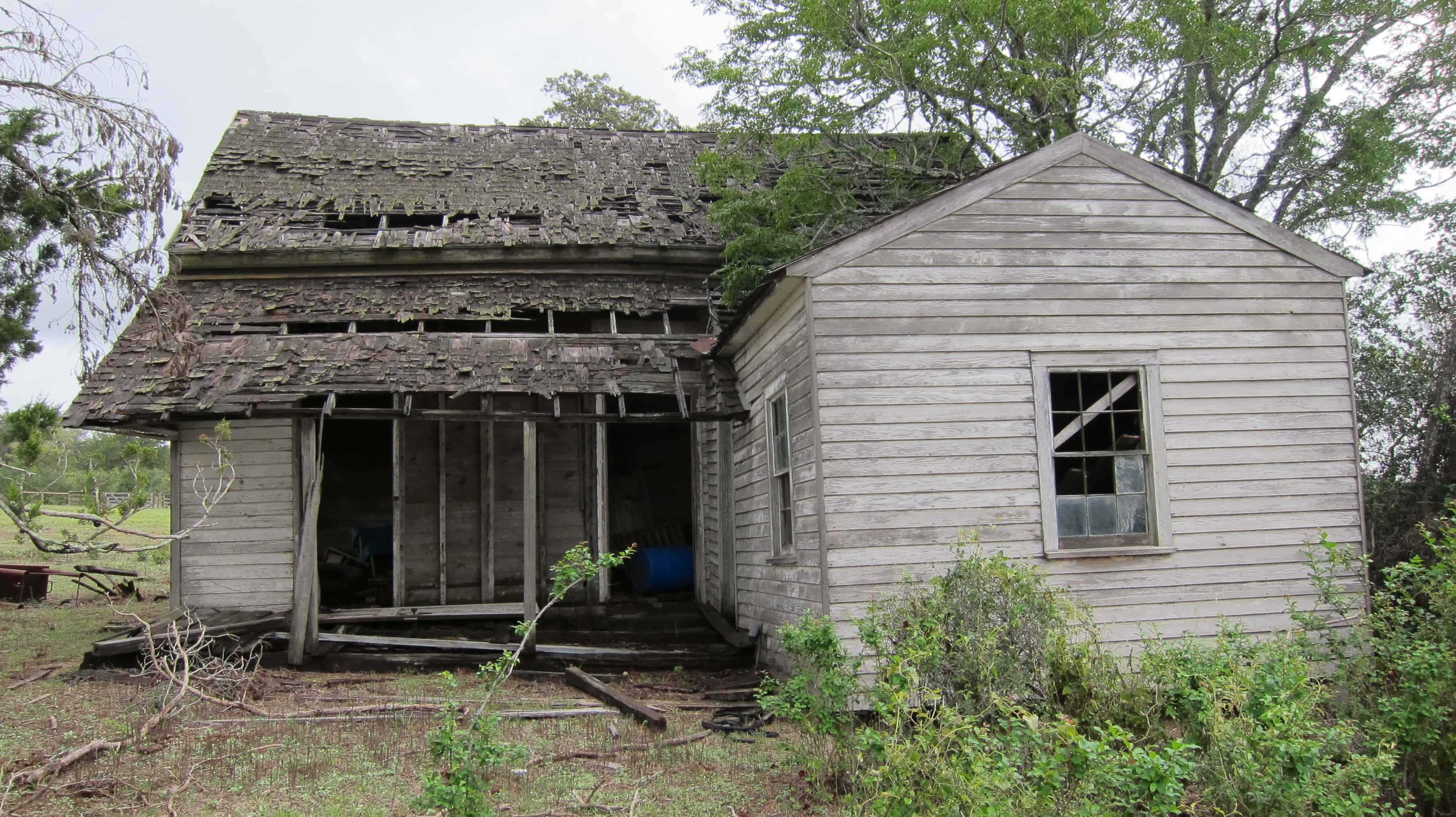 Old Times 桌布 壁紙 — 一間被遺棄、風化的木屋，屋頂坍塌，窗戶破損，矗立在長滿雜草的鄉間田野中。