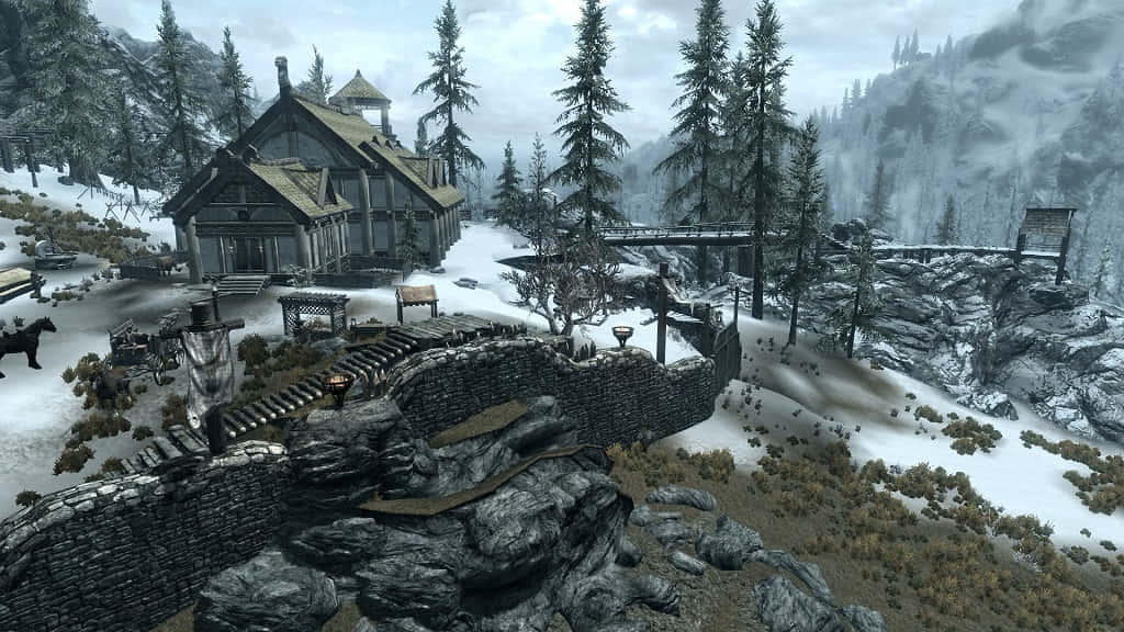 Heljarchen Hall 桌布 壁紙 — 一間被雪覆蓋的中世紀風格房屋，坐落在霧氣瀰漫的山谷中，周圍環繞著常綠樹和石頭廢墟。