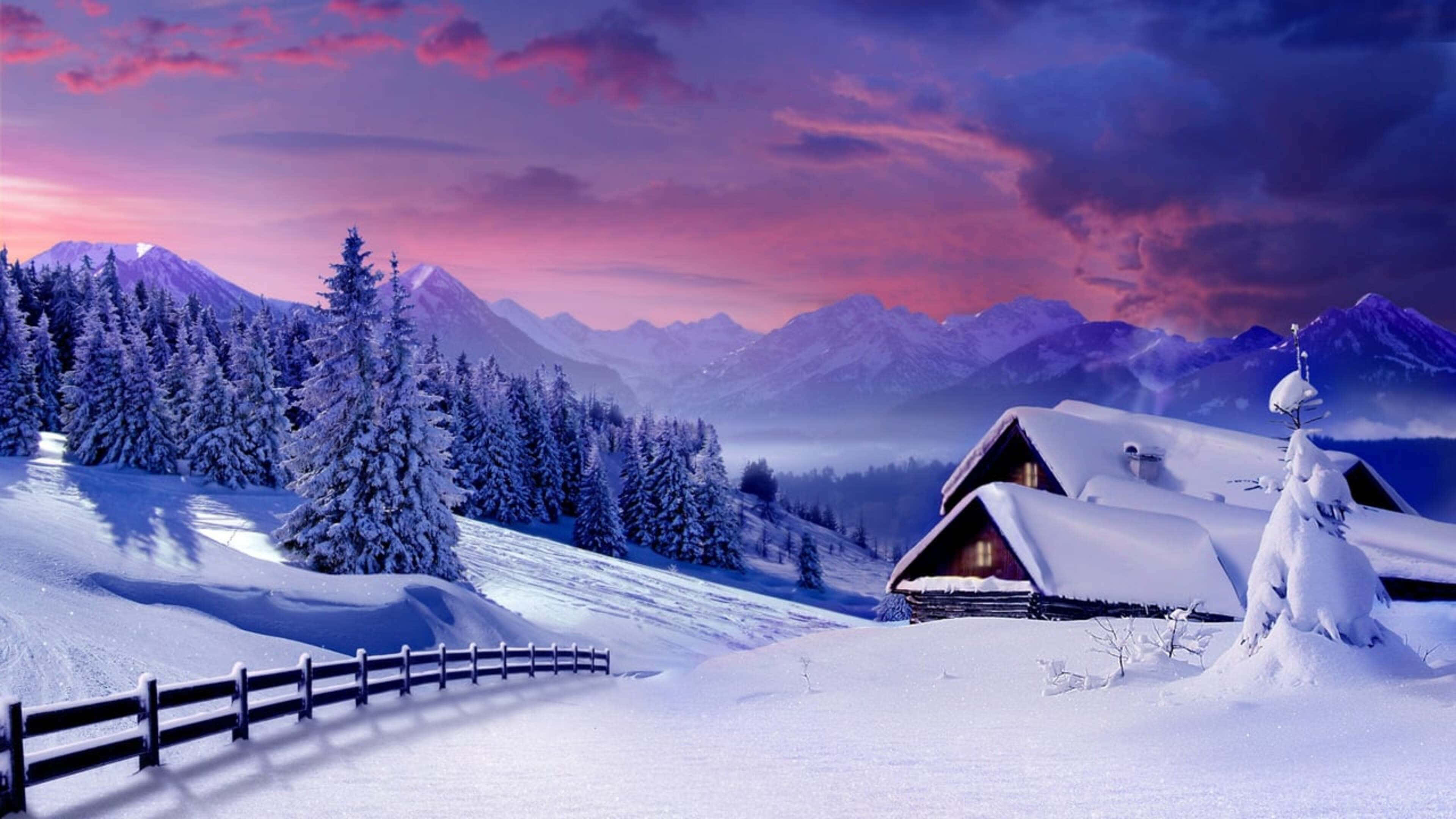 4K Winter 桌布 壁紙 — 一間被雪覆蓋的木屋，坐落在冬季森林中，群山環繞，天空呈現鮮豔的粉紅色和紫色日落。