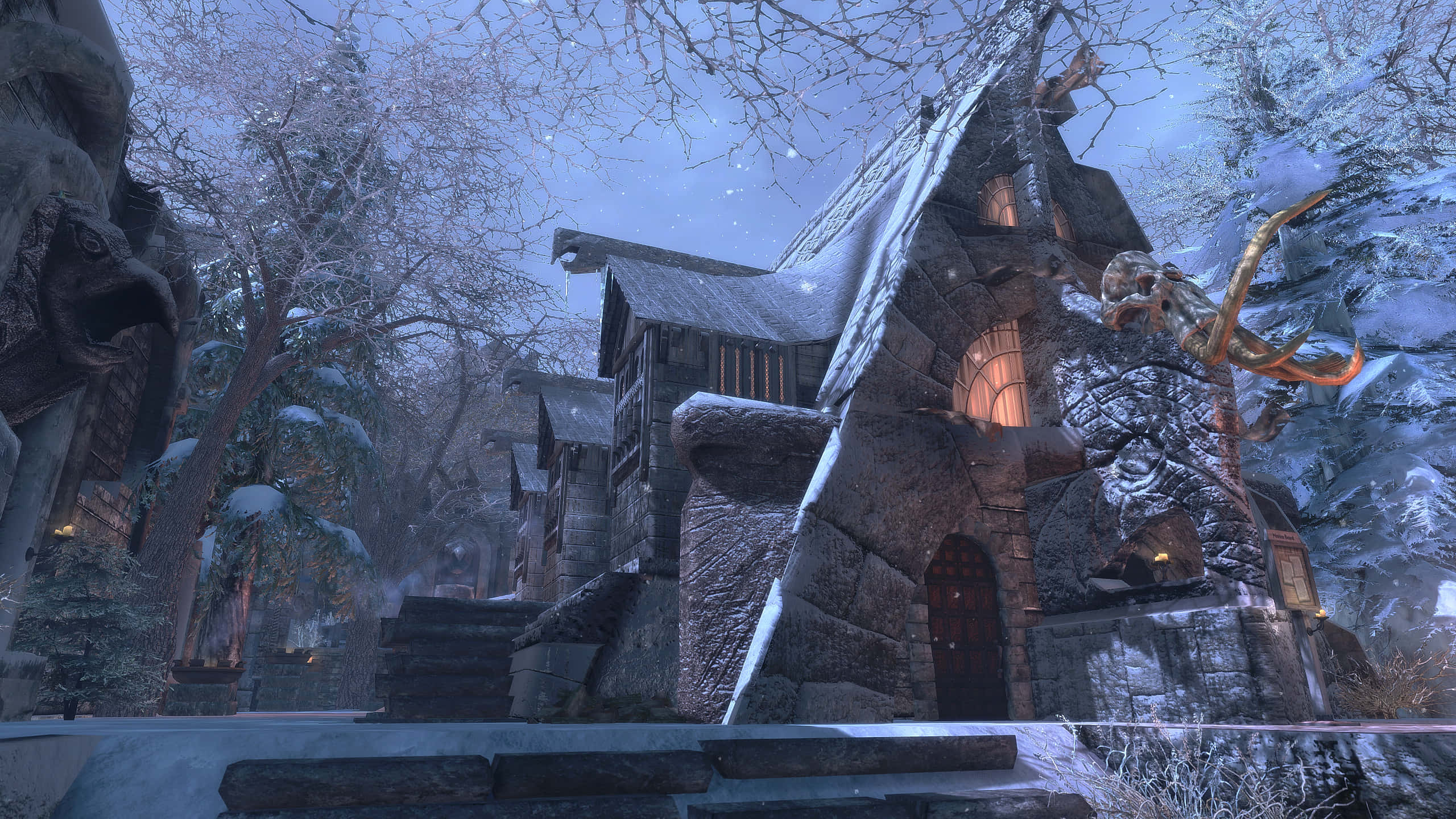 Skyrim Windhelm 桌布 壁紙 — 一間被雪覆蓋的石屋，窗戶發光，坐落在冬日森林中，在暮色天空下。