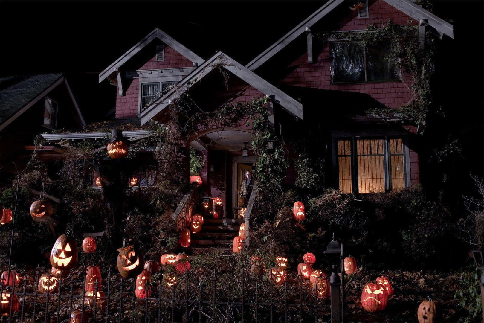 Trick Or Treat 桌布 壁紙 — 一間詭異的紅房子在夜晚被發光的南瓜燈和攀爬的藤蔓覆蓋，迎接萬聖節。