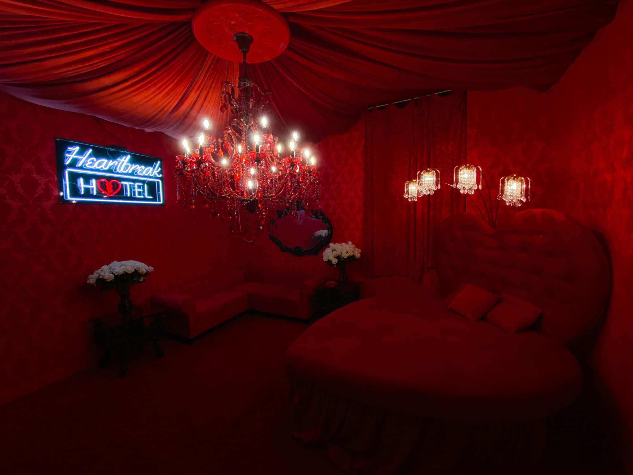 Red Room 桌布 壁紙 — 一間豪華的深紅色臥室，配有吊燈和寫著「Heartbreak Hotel」的霓虹燈標誌。