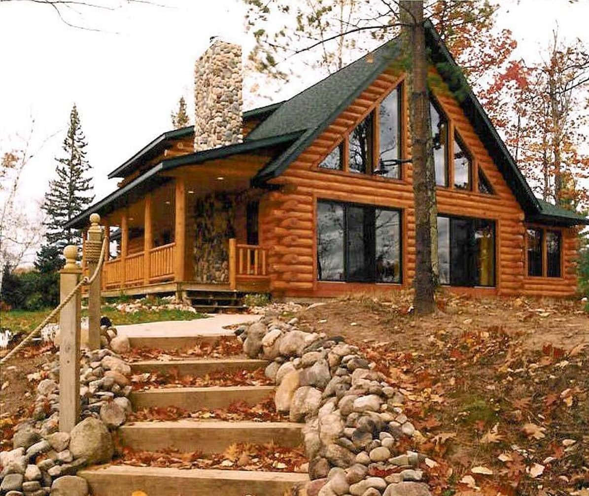 cabin 桌布 壁紙 — 一間質樸的木屋，配有石頭煙囪和門廊，坐落在秋樹之間，落葉覆蓋著石階。