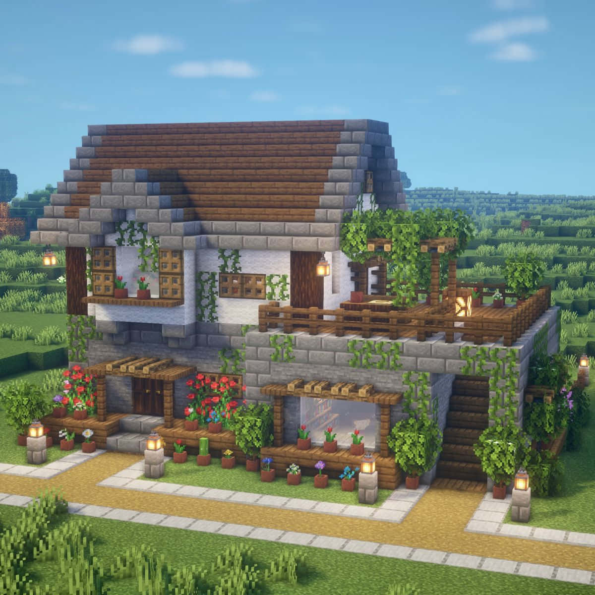 Minecraft Architecture 桌布 壁紙 — 一間迷人的像素化Minecraft小屋，擁有石牆、木質裝飾和鮮豔的花朵，在晴朗的藍天下綻放。