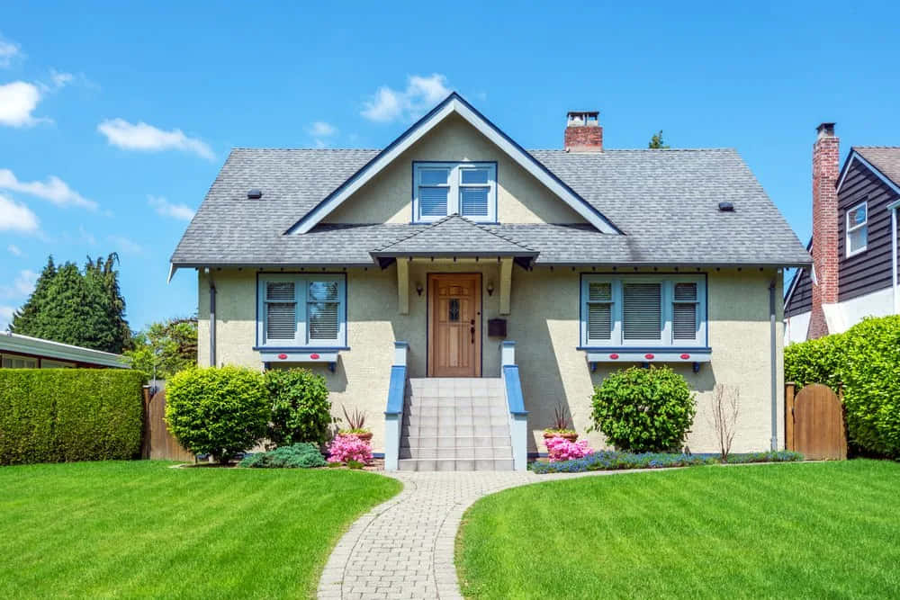 Nice Houses 桌布 壁紙 — 一間迷人的米色平房，帶有藍色飾邊和一條石徑，在晴朗的藍天下通往其木製前門。