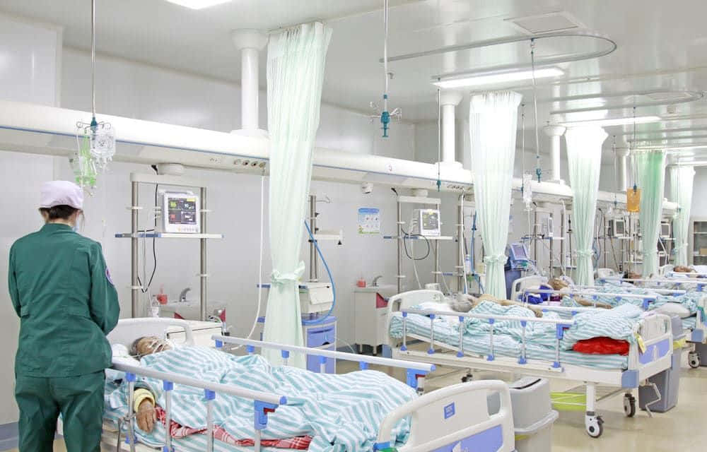 一間醫院病房裡有多張病床和一名護士 壁紙