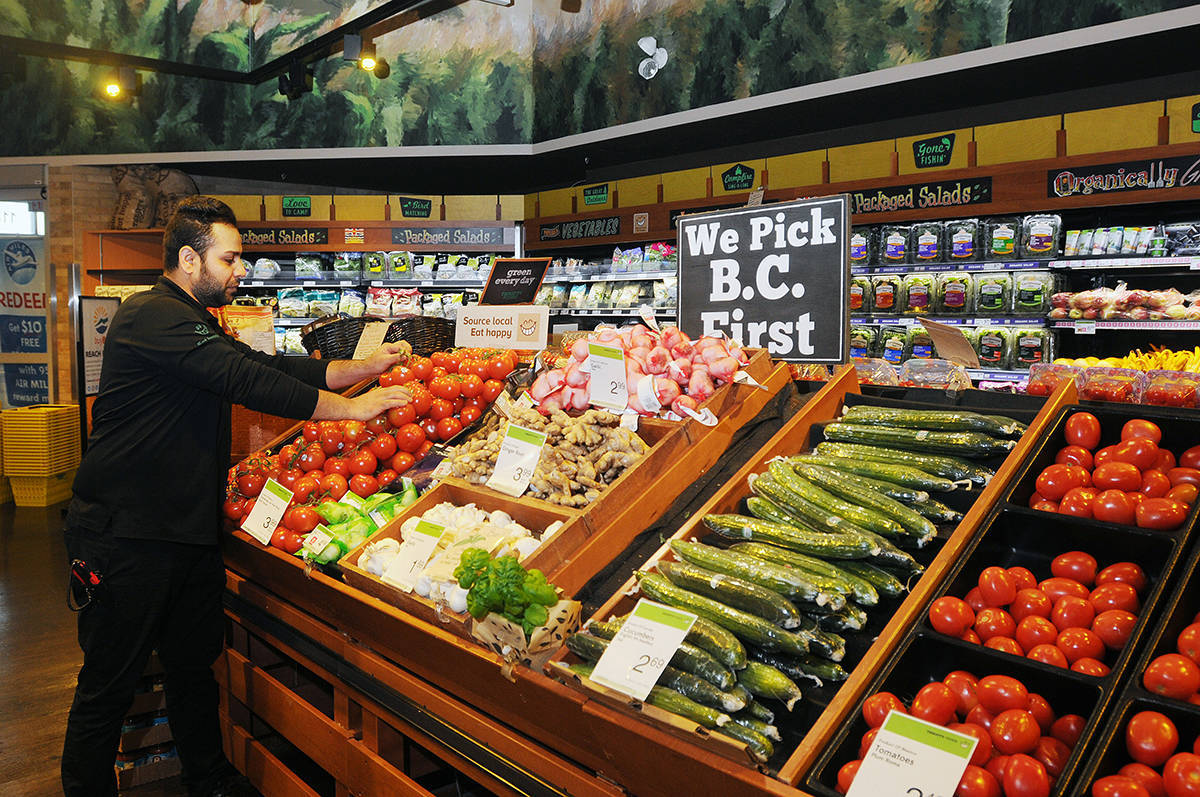 Vegetables 桌布 壁紙 — 一間雜貨店的員工在明亮的燈光下將番茄和小黃瓜等新鮮農產品擺放在木箱中。