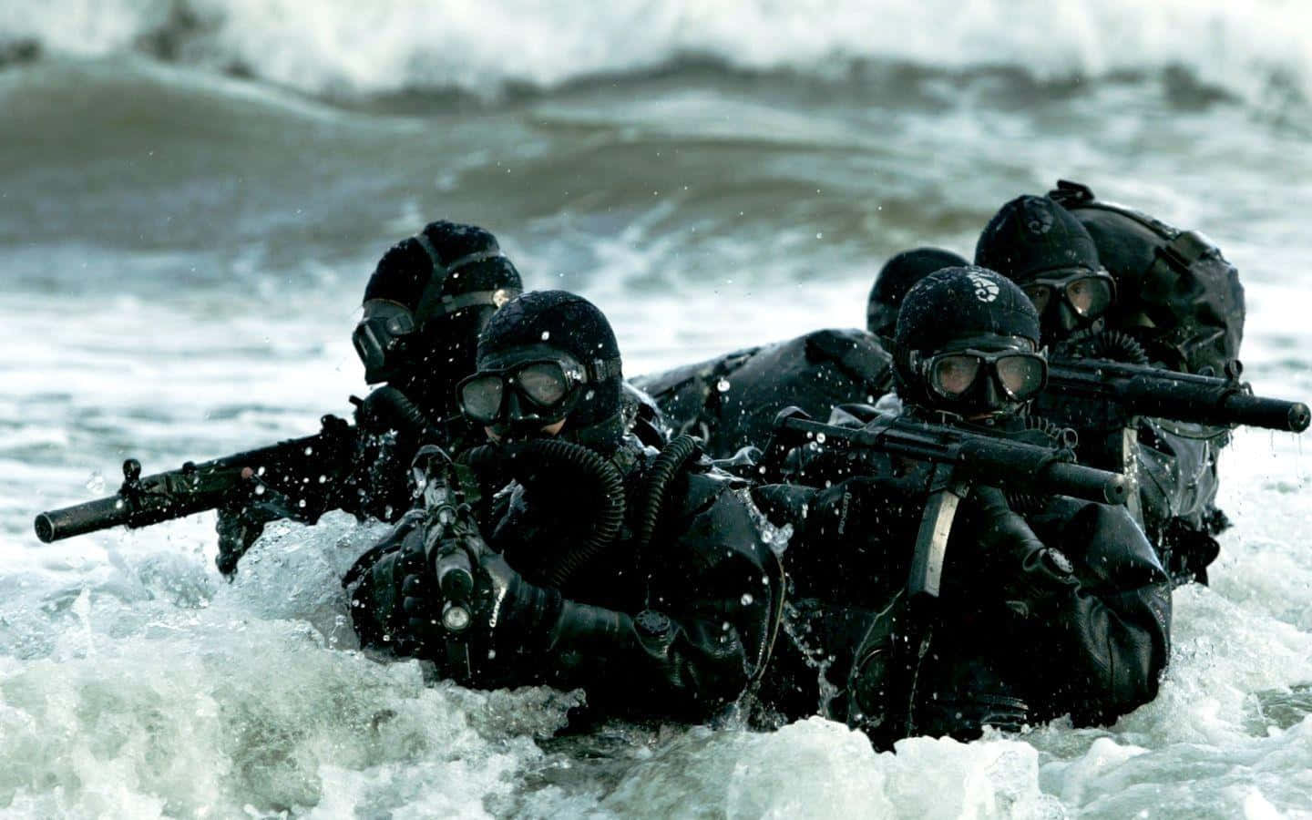 Special Forces 桌布 壁紙 — 一隊全副武裝、身穿黑色裝備的士兵，在洶湧的海浪中涉水前進，步槍已準備就緒。
