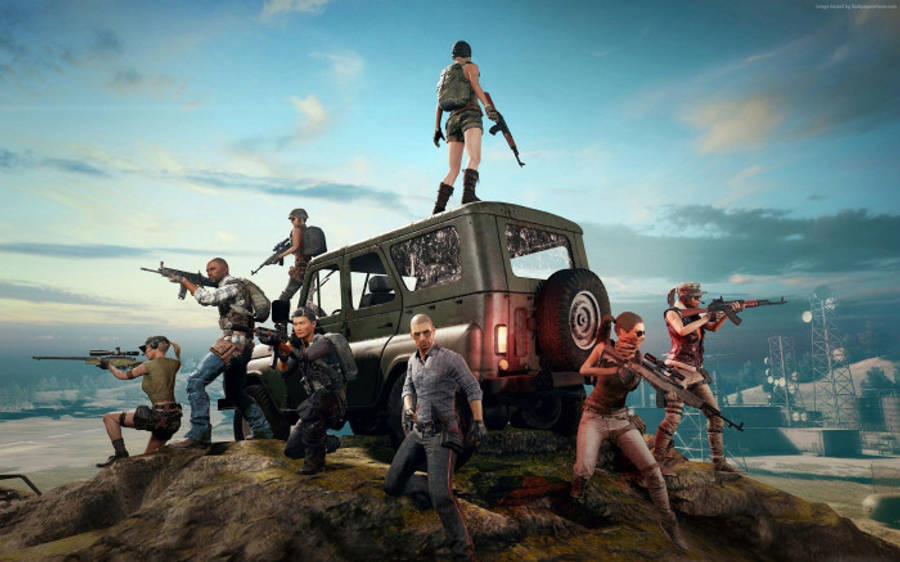 pubg 4K gaming 桌布 壁紙 — 一隊身穿戰術裝備的武裝遊戲玩家站在一輛堅固的吉普車上，位於岩石懸崖上，俯瞰著日落時分的遠方城市景觀。