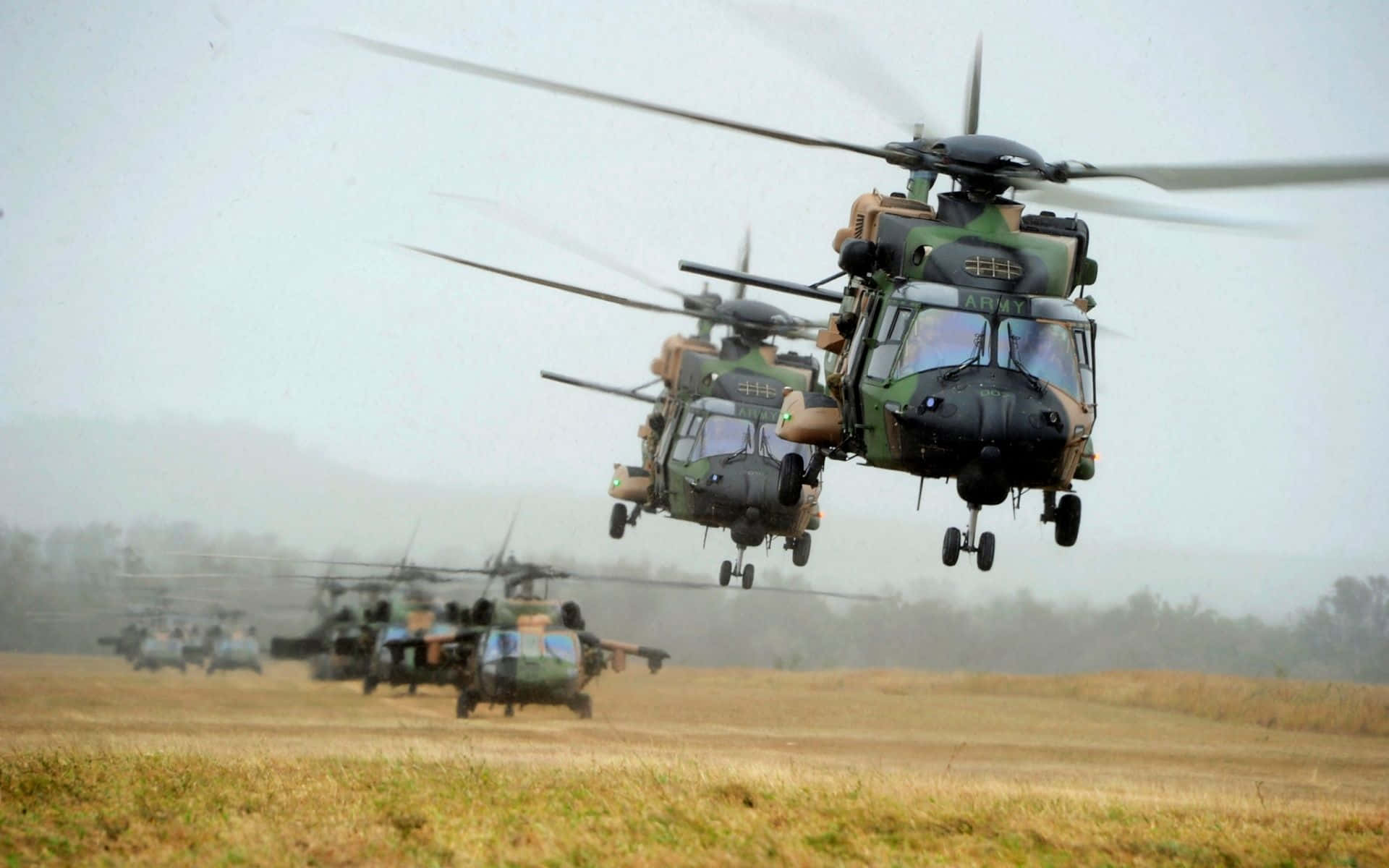 Helicopter 桌布 壁紙 — 一隊迷彩軍用直升機從草地起飛，天空多雲。