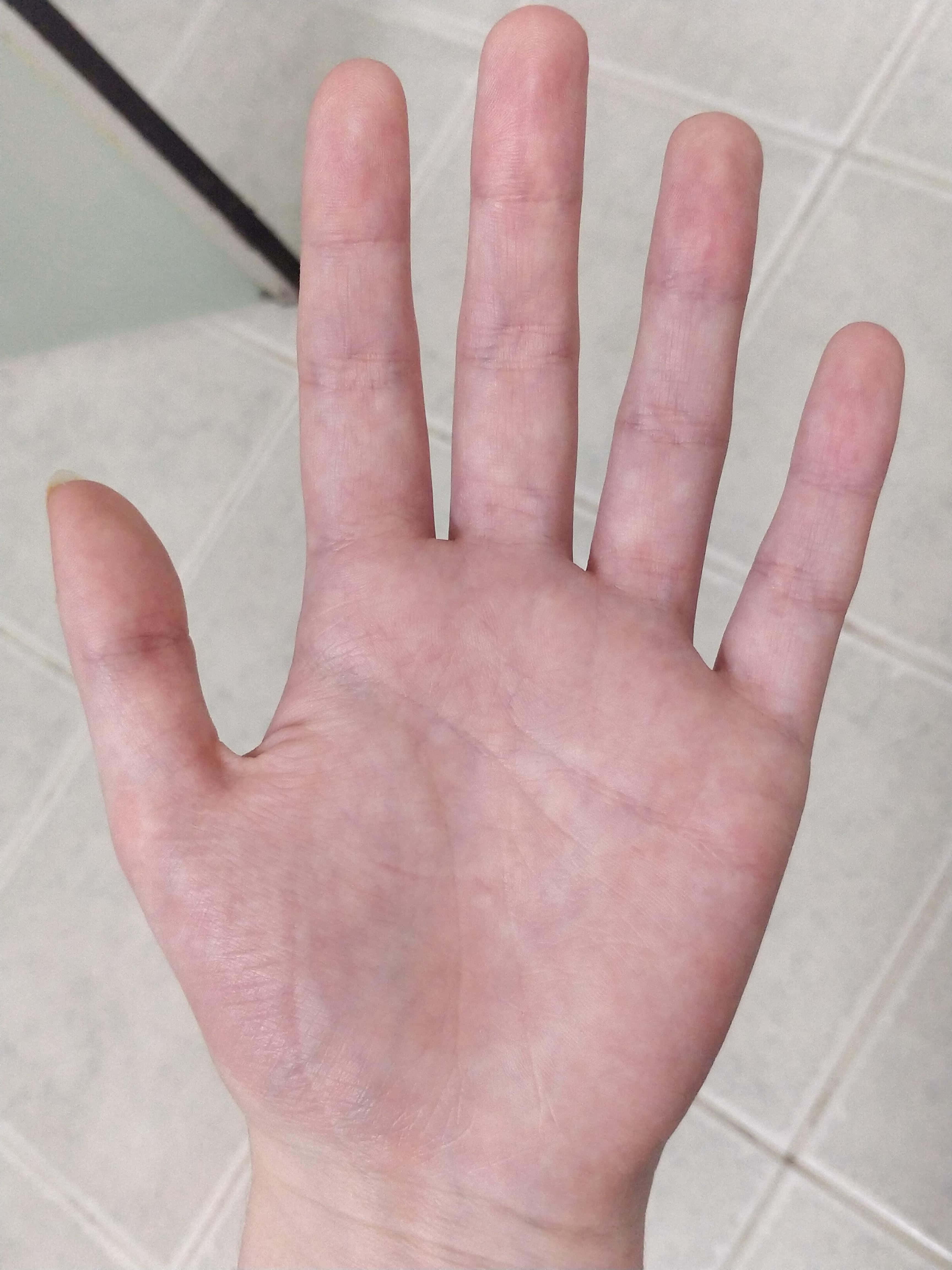 Blue Veins 桌布 壁紙 — 一隻人類手掌朝上放在淺色瓷磚地板上的特寫，顯示皮膚紋理和線條。