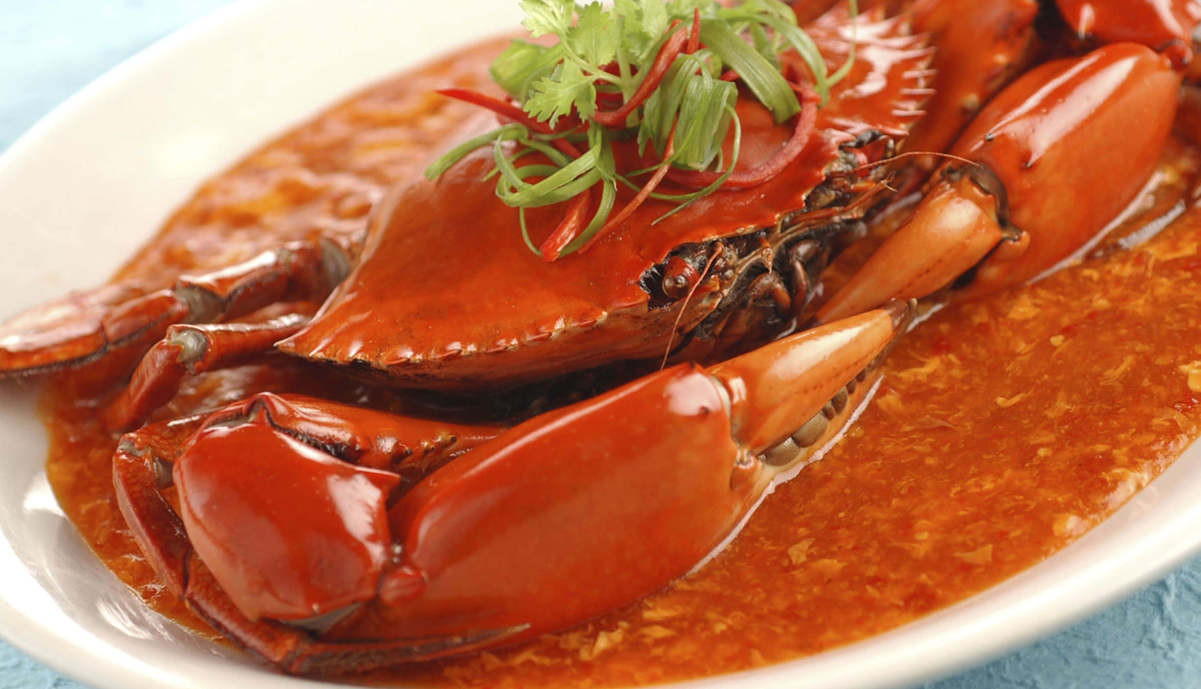Singapore 桌布 壁紙 — 一隻光澤的紅蟹，配上濃郁美味的醬汁，以新鮮香菜和紅辣椒絲點綴，放在白色盤子上。