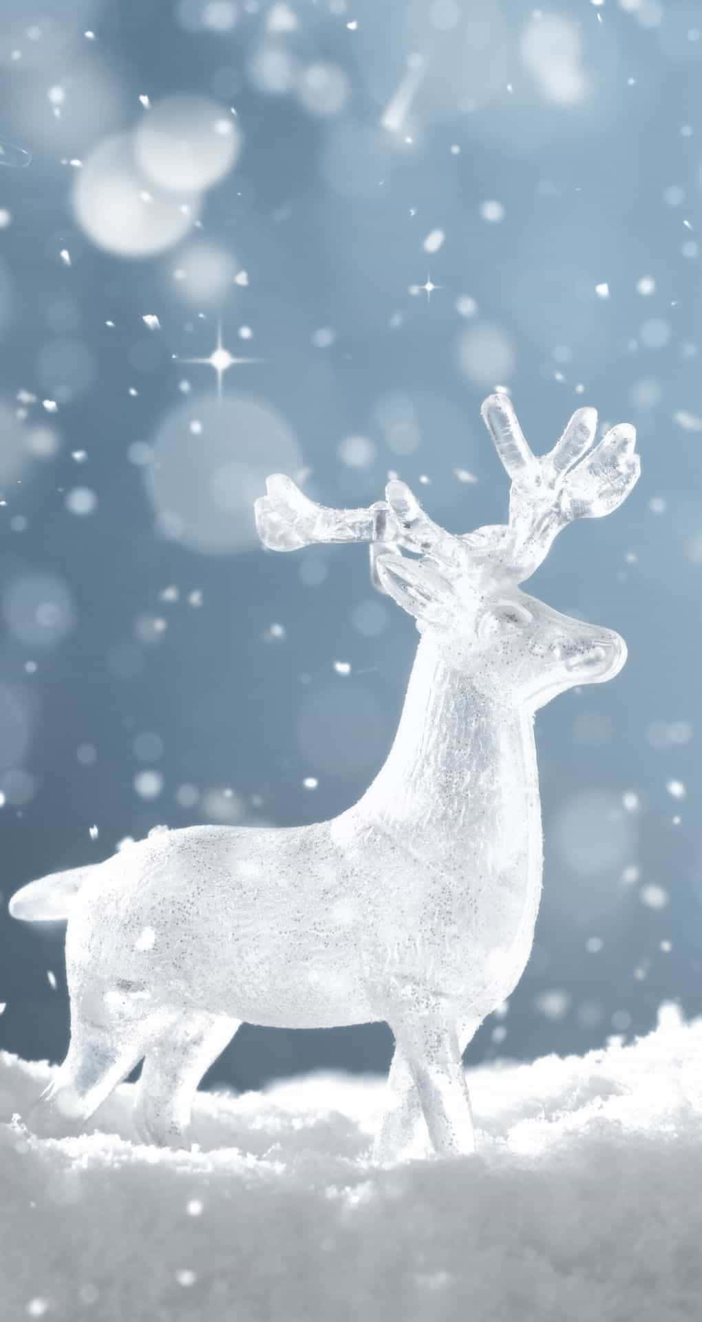 聖誕節 桌布 壁紙 — 一隻半透明的冰馴鹿優雅地站在飄落的雪中，背景是柔和的藍色散景和閃爍的燈光。