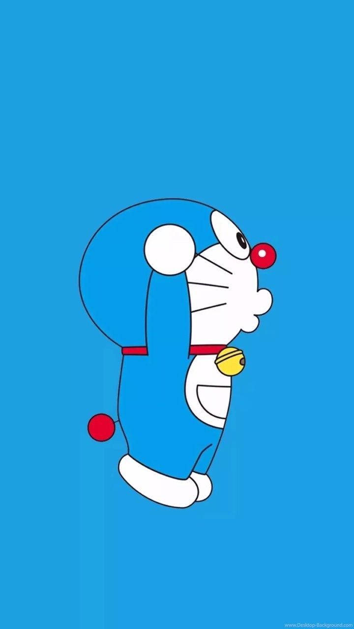 Doraemon 桌布 壁紙 — 一隻卡通機器貓，藍色身體、白色臉、紅色鼻子和鈴鐺，站在純藍色背景前。