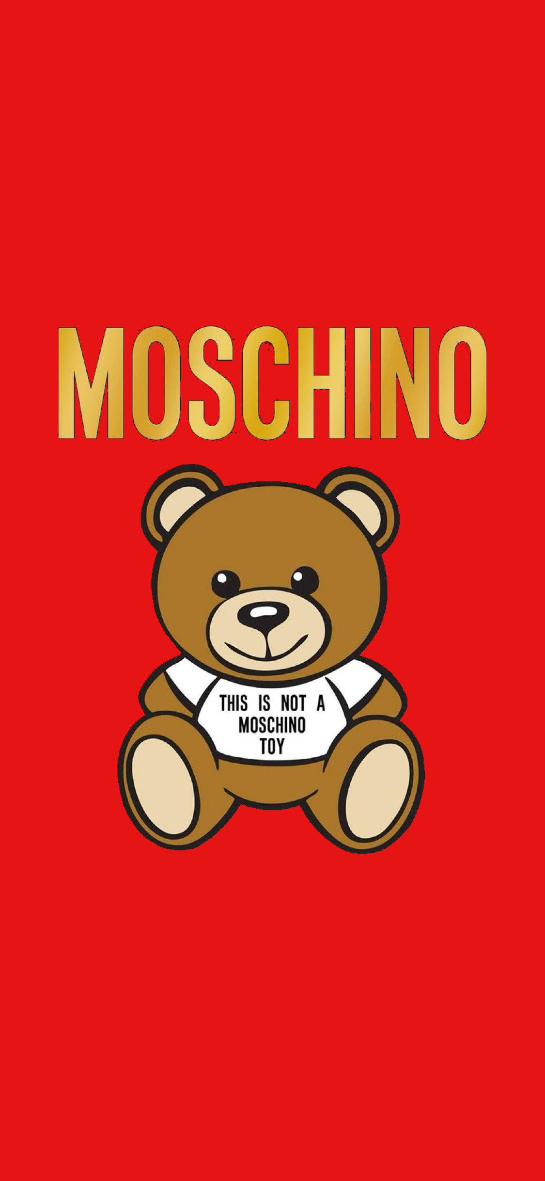 moschino 桌布 壁紙 — 一隻卡通泰迪熊穿著帶有文字的白襯衫，坐在大膽的紅色背景中央，上方有金色 'MOSCHINO' 字樣。