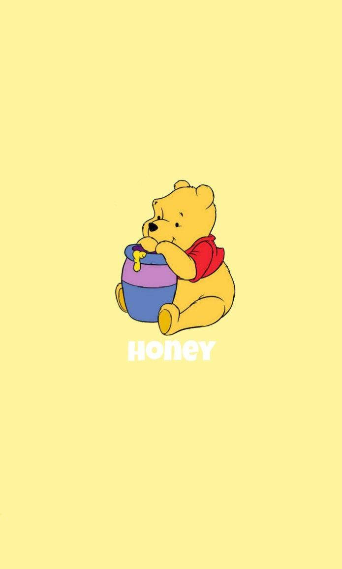 Disney Winnie The Pooh 桌布 壁紙 — 一隻可愛的卡通熊穿著紅色襯衫，快樂地坐在柔和的黃色背景前，抱著一個色彩繽紛的蜂蜜罐。