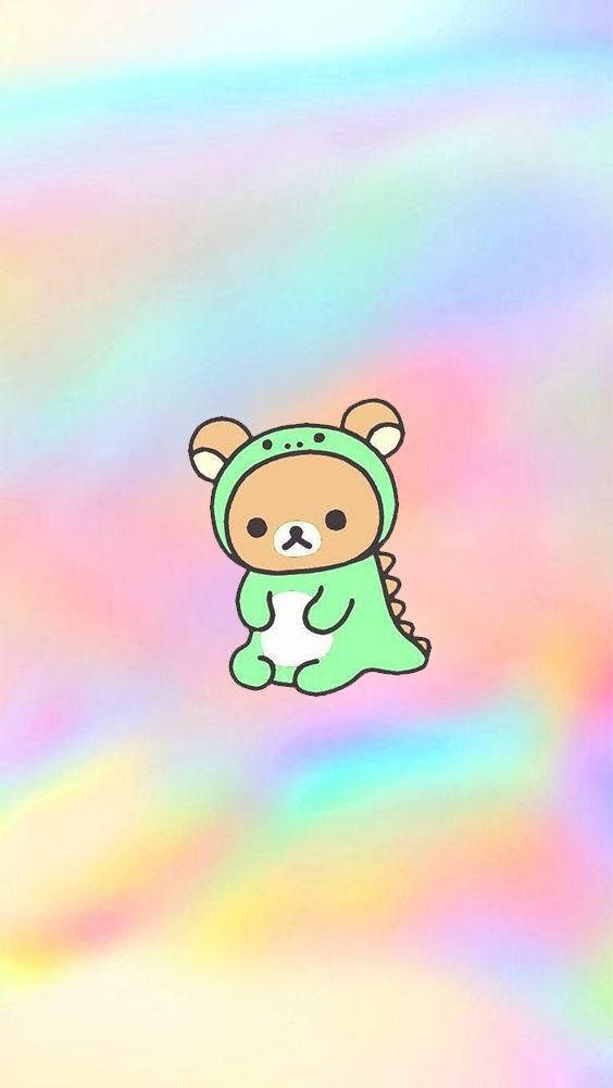 懶懶熊 桌布 壁紙 — 一隻可愛的卡通熊穿著綠色恐龍服裝，漂浮在柔和的粉彩彩虹漸變背景上。