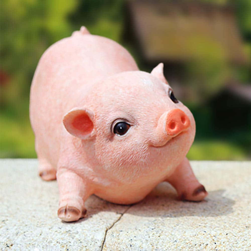 Pig 桌布 壁紙 — 一隻可愛的粉紅色小豬公仔，有大眼睛，坐在石頭表面上，背景是模糊的綠色。