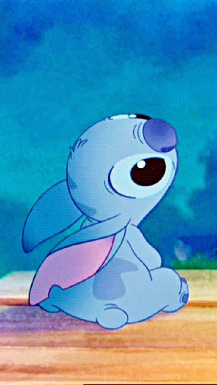 Stitch 桌布 壁紙 — 一隻可愛的藍色外星人，大眼睛，坐在木地板上，背景是青綠色。
