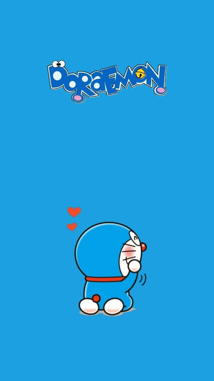 Doraemon 桌布 壁紙 — 一隻可愛的藍色機器貓哆啦A夢坐在底部中央，兩個紅色愛心在他上方飄浮，背景為純藍色，頂部有他的標誌。