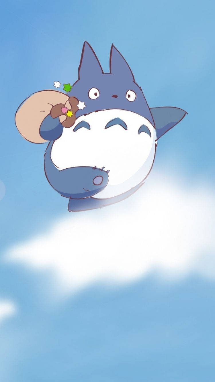 Studio Ghibli iPhone 桌布 壁紙 — 一隻可愛的藍色龍貓在明亮的藍天中輕輕漂浮，手持一小束色彩繽紛的花朵。
