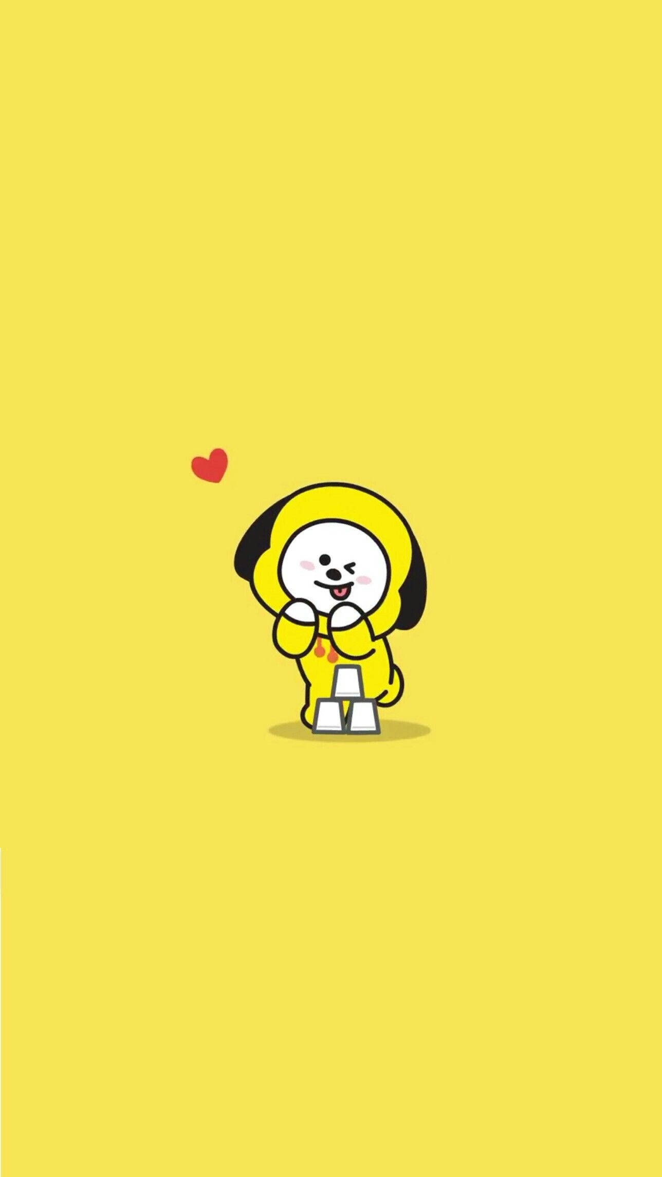 BT21 桌布 壁紙 — 一隻可愛的黃色卡通狗，有黑色耳朵，微笑著拿著一個小紅心，背景是純黃色。