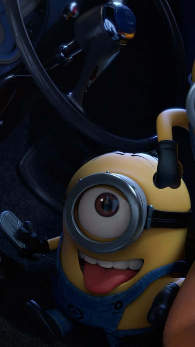 搞笑 桌布 壁紙 — 一隻單眼黃色Minion一邊瘋狂咧嘴笑，一邊開車，一隻手放在方向盤上，另一隻手放在排檔桿上。
