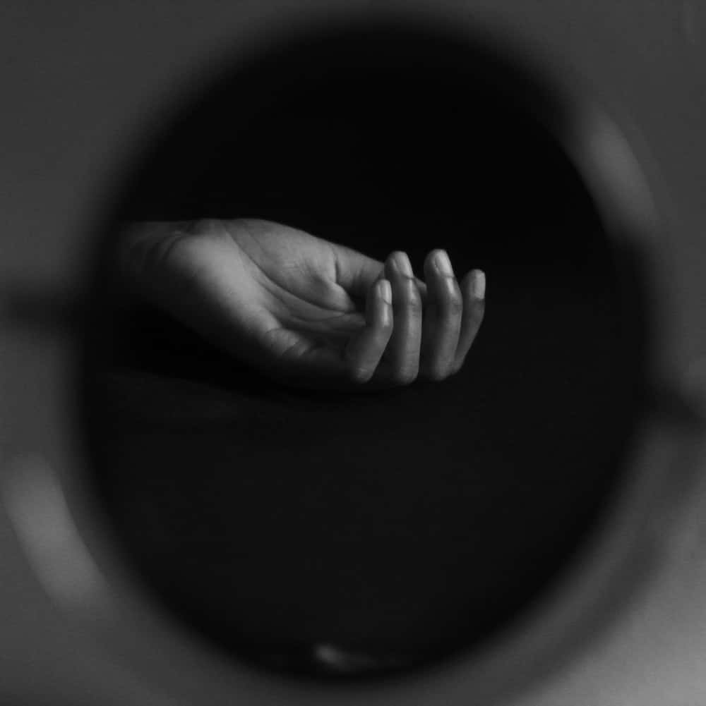 reflection 桌布 壁紙 — 一隻單色手從黑暗中穿過圓形開口出現，營造出極簡主義的鮮明構圖。