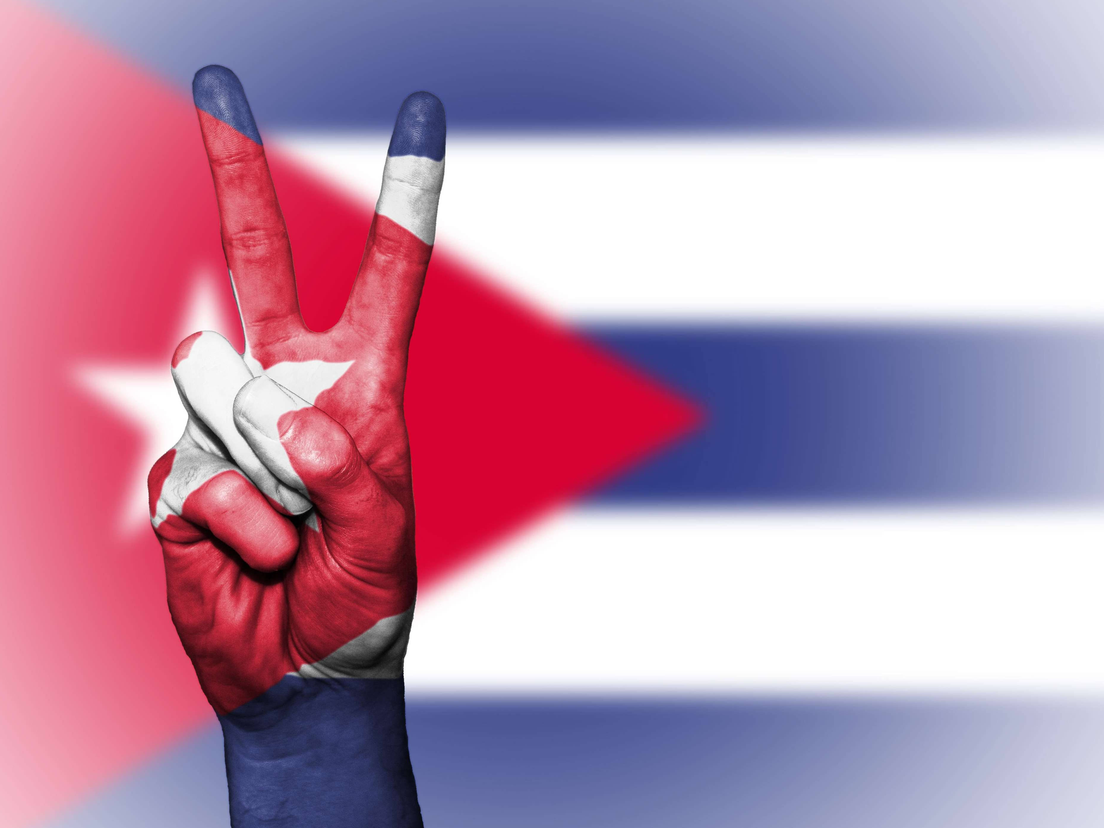 Cuban 桌布 壁紙 — 一隻塗有古巴國旗的手在模糊的古巴國旗背景下做出和平手勢。