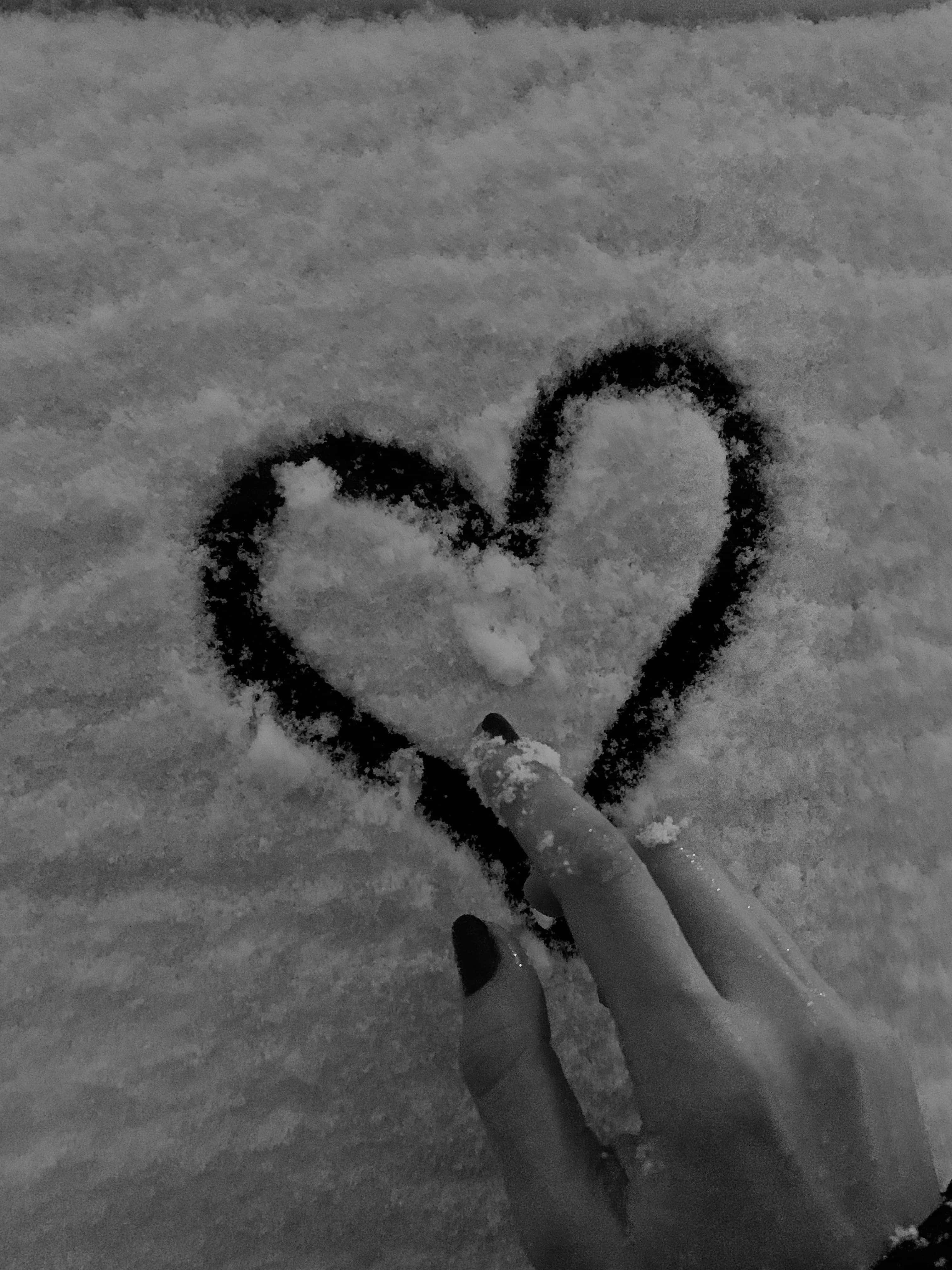 心形美學 桌布 壁紙 — 一隻塗有深色指甲油的手在新雪上畫出一顆心，以單色和柔和質感捕捉。