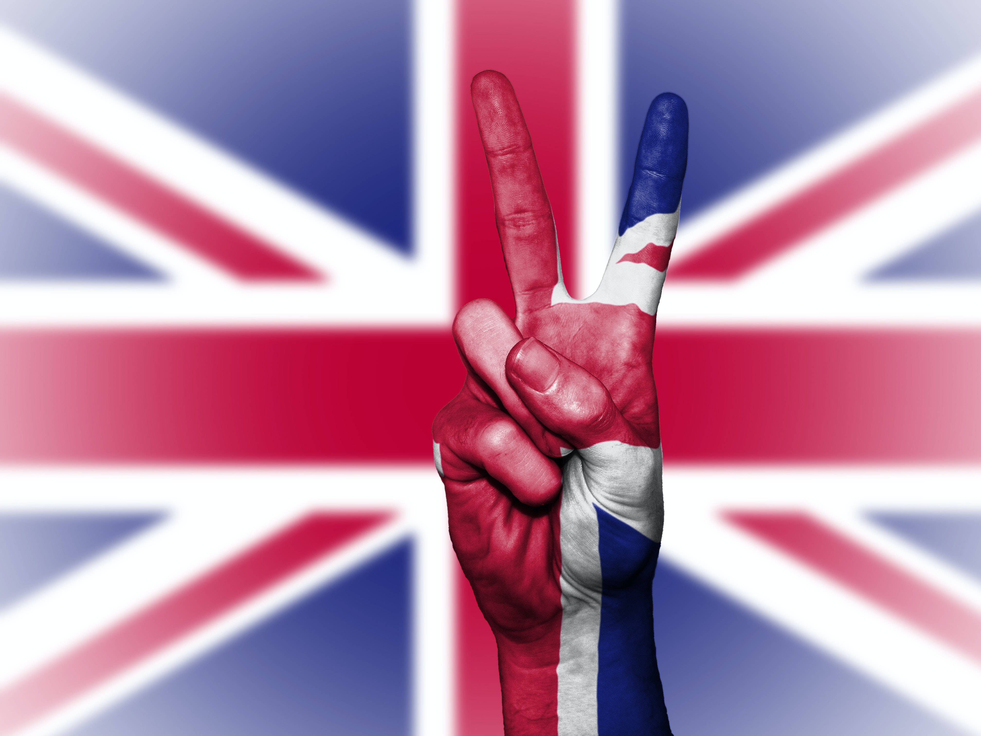 Peace Symbol 桌布 壁紙 — 一隻塗有英國國旗的手在模糊的英國國旗背景下做出和平手勢。