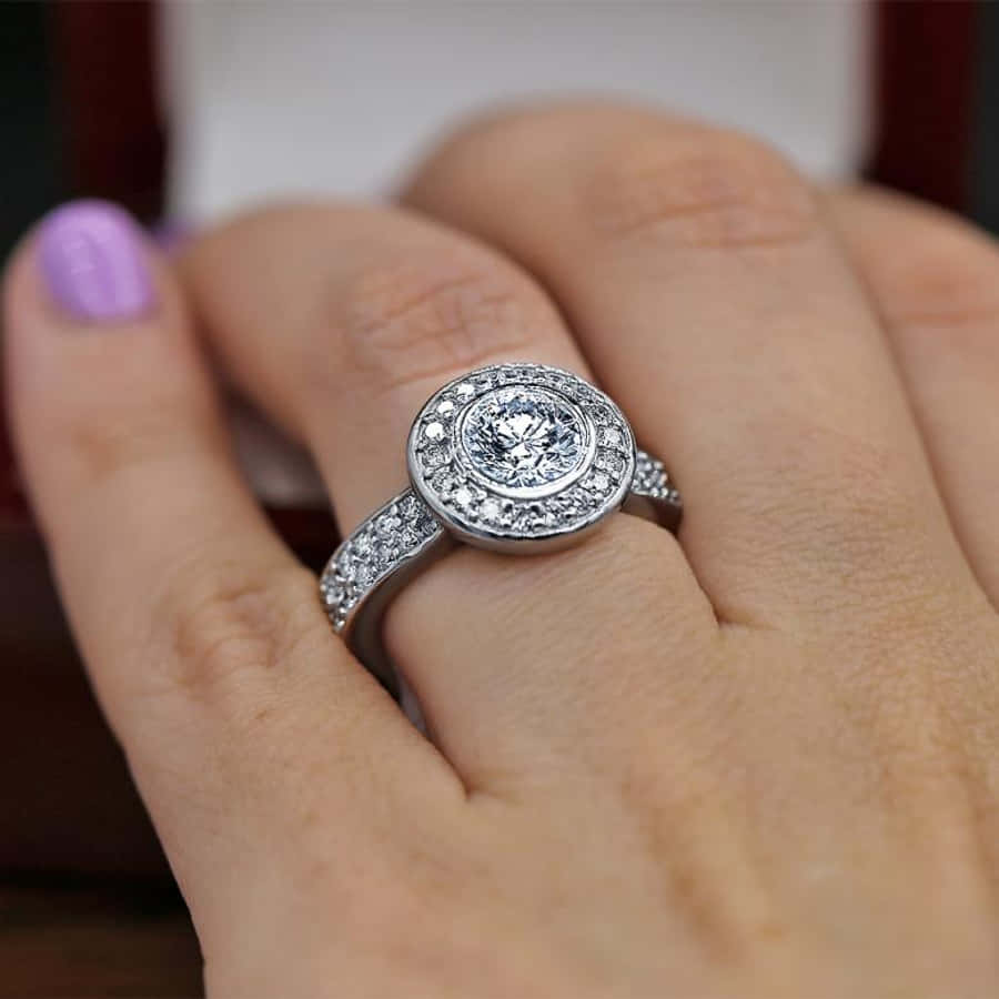 rings 桌布 壁紙 — 一隻塗有薰衣草指甲油的手，精緻地展示了一枚閃耀的鑽石訂婚戒指，採用光環鑲嵌。