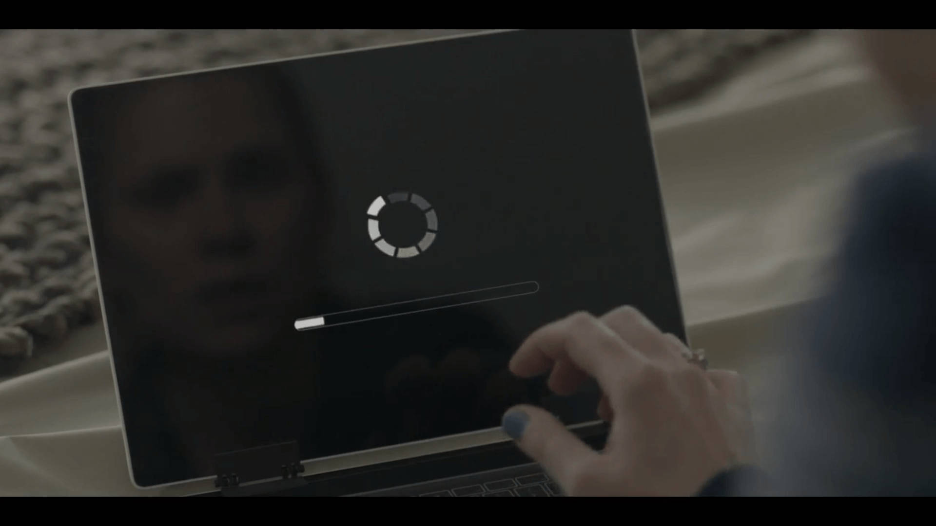 Netflix 桌布 壁紙 — 一隻塗有藍色指甲油的手懸浮在筆記型電腦上方，螢幕上顯示載入旋轉器和進度條，並反射出模糊的人臉。