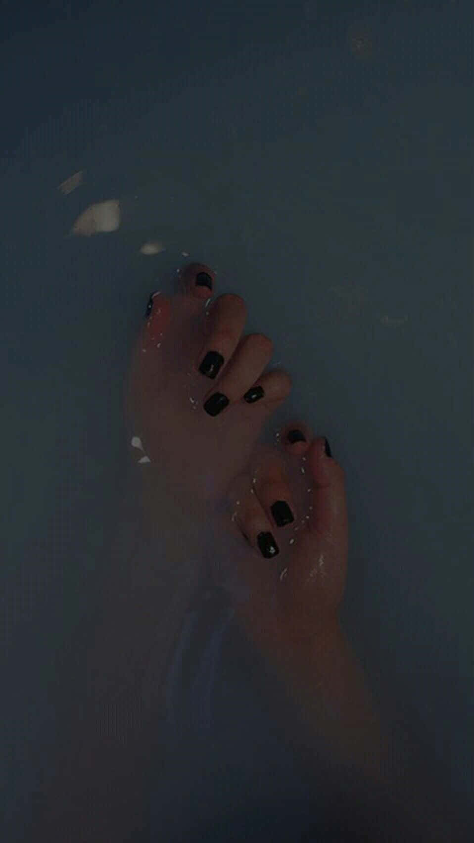 Tumblr 桌布 壁紙 — 一隻塗有黑色指甲油的手輕輕浸入暗水中，柔和的光線在水面反射。